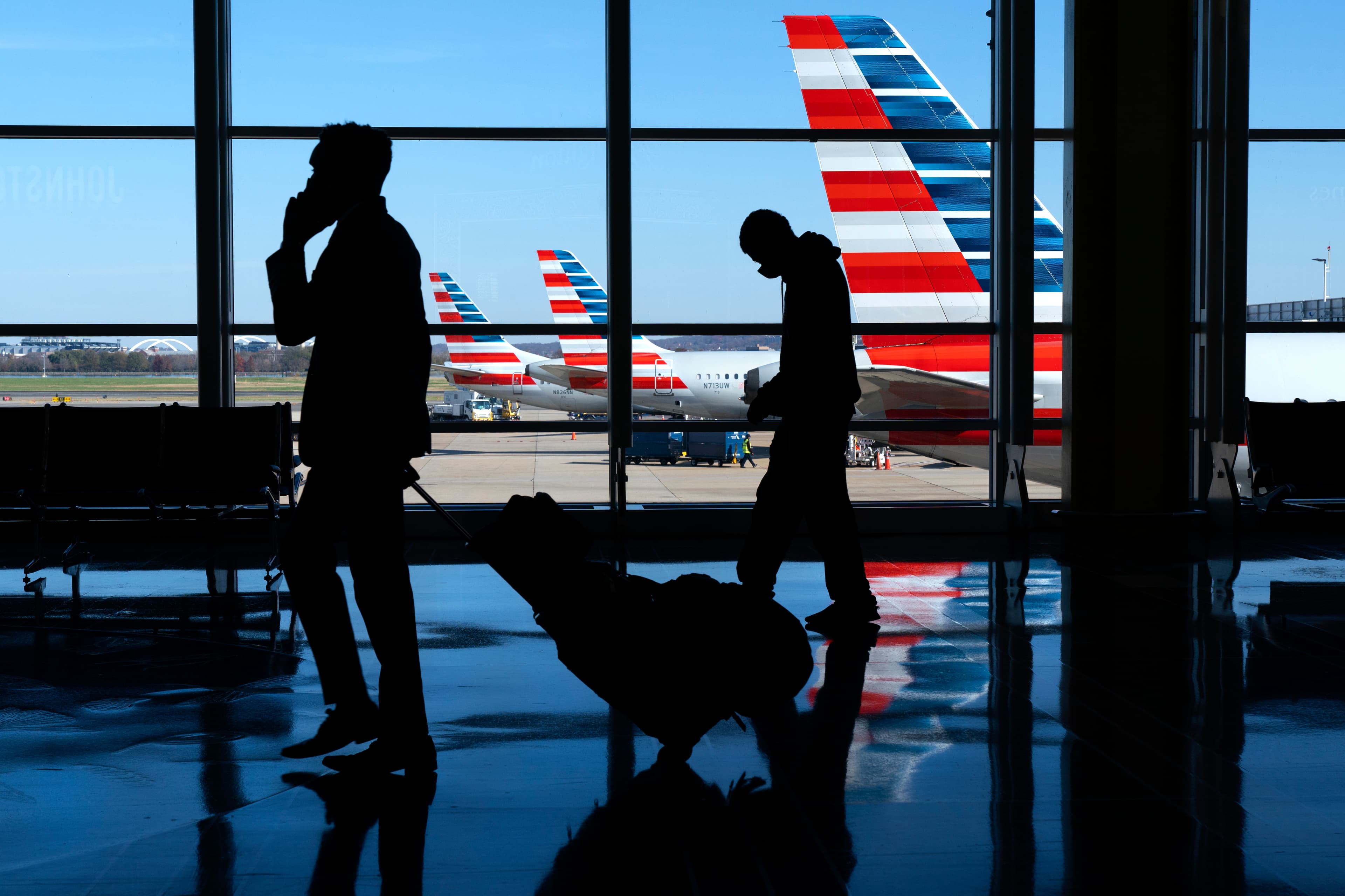 Wearing masks, travelers walk to and from their planes at Ronald Reagan Washington National Airport, Nov. 24, 2020, in Arlington, Virginia, in advance of the Thanksgiving holiday.