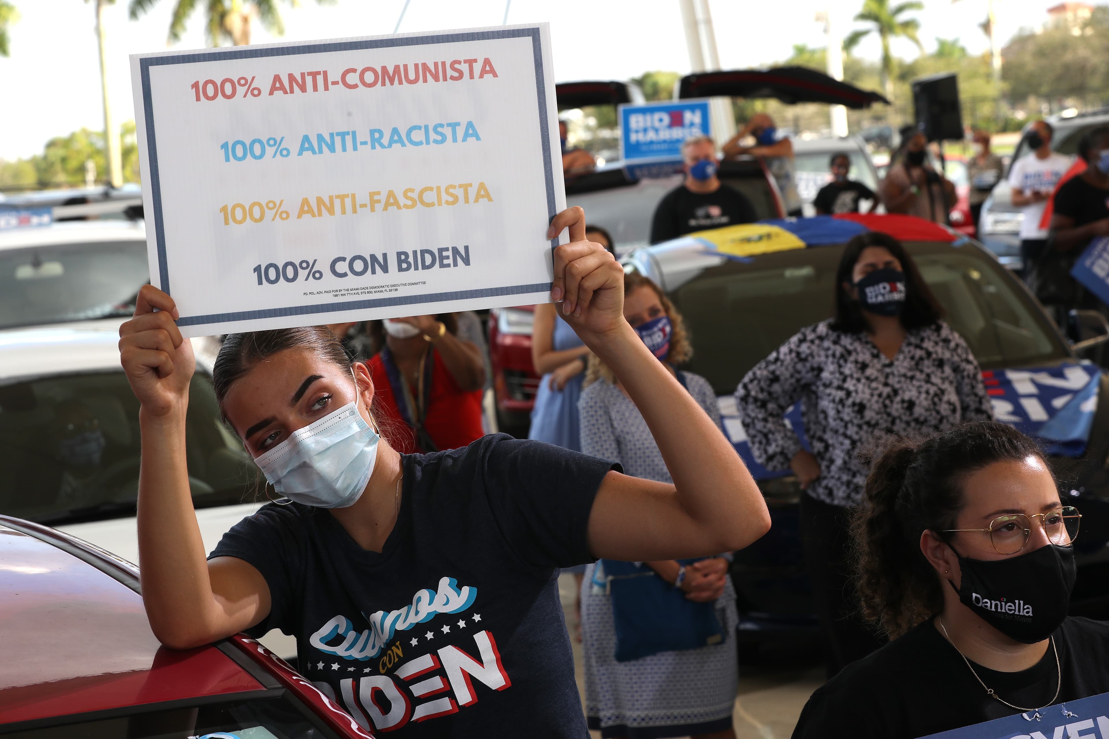 A woman holds up a sign in support of Biden and against Trump.
