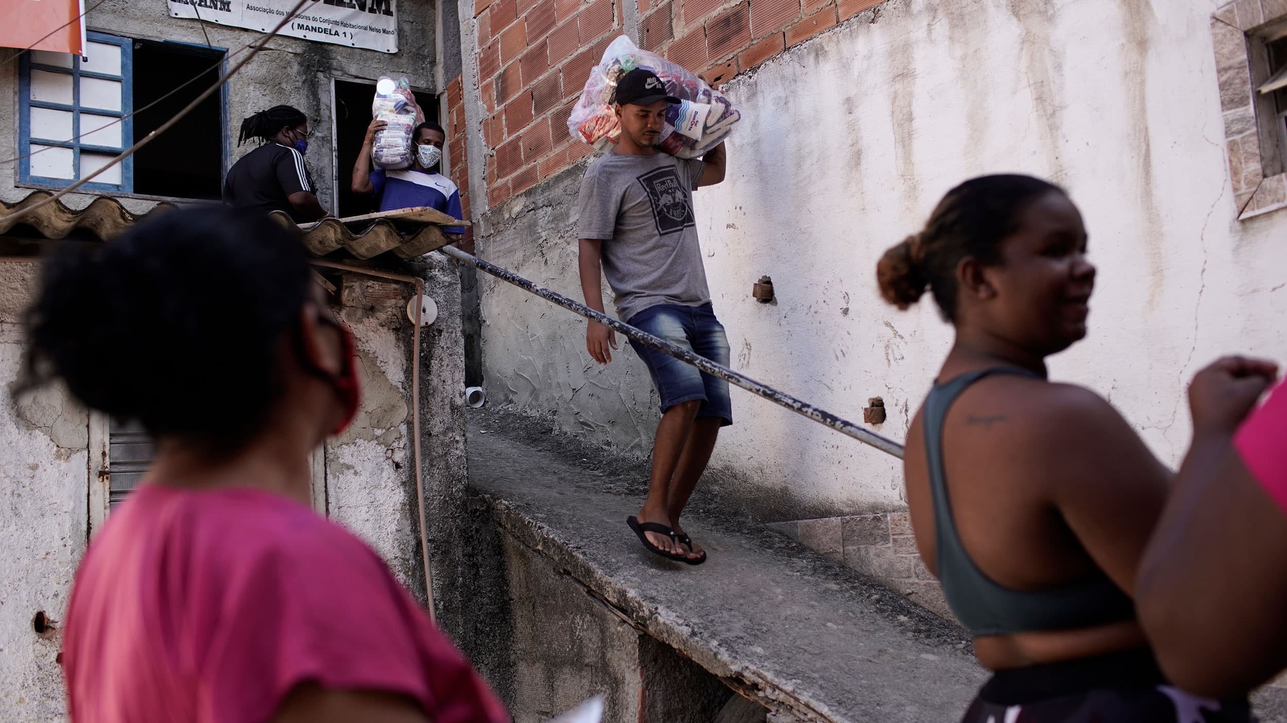 People are shown waiting at the bottom of a ramp with a man walking down the ramp carrying a bag over his shoulder.