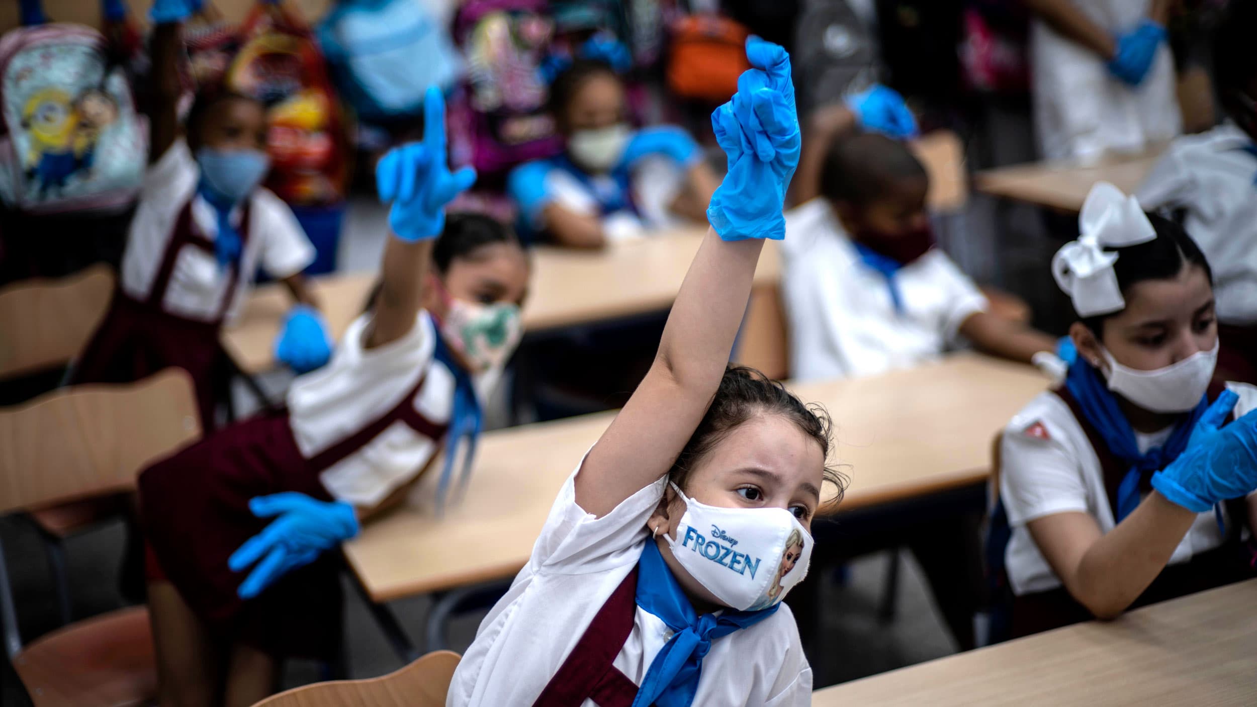 A row of children are shown with their hands raised and wearing school uniforms.
