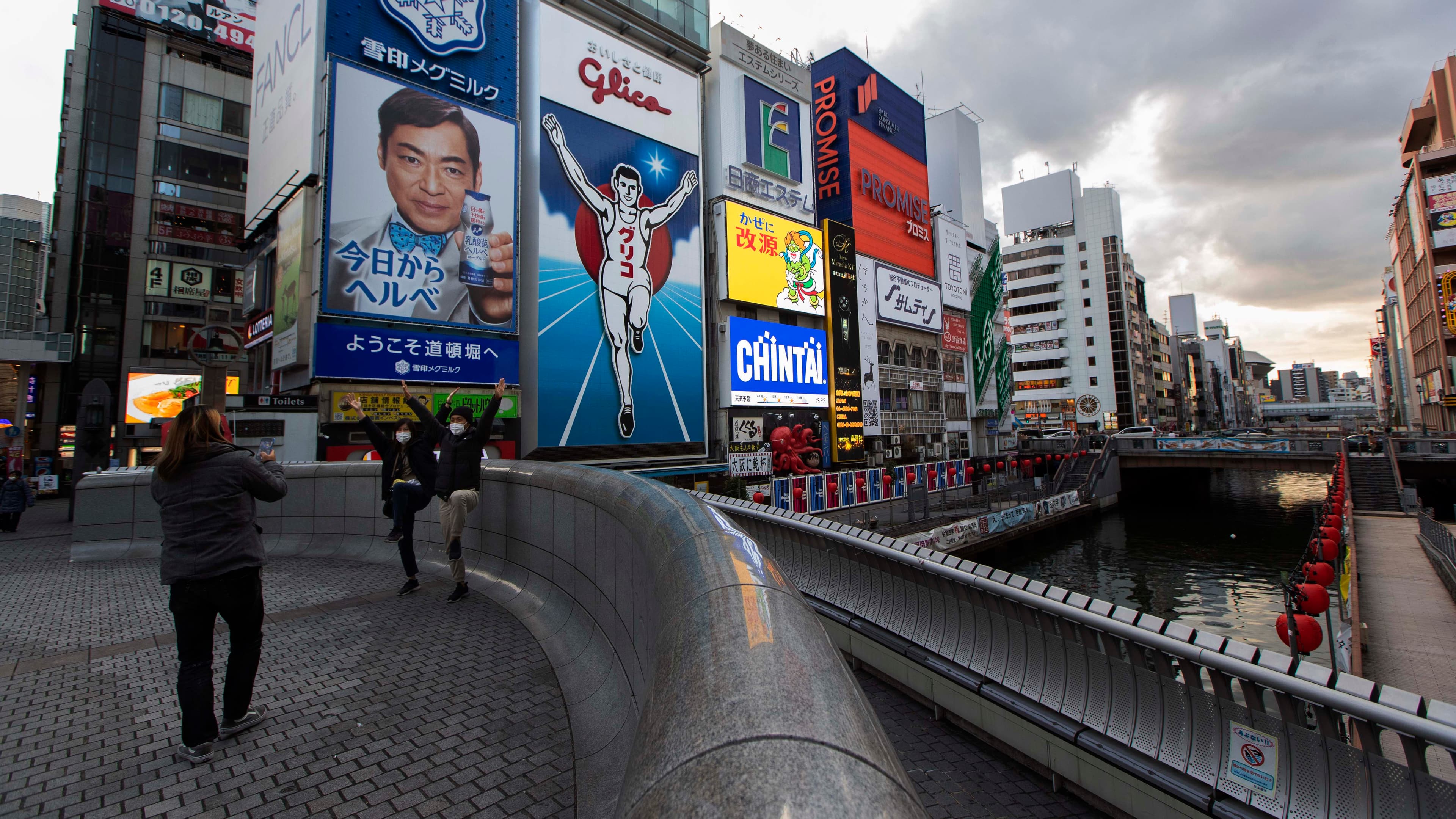 People pose for a photo, mimicking the character in an advertisement as they visit Ebisu-bashi bridge, a popular tourist spot in Osaka, western Japan, Nov. 30, 2020.