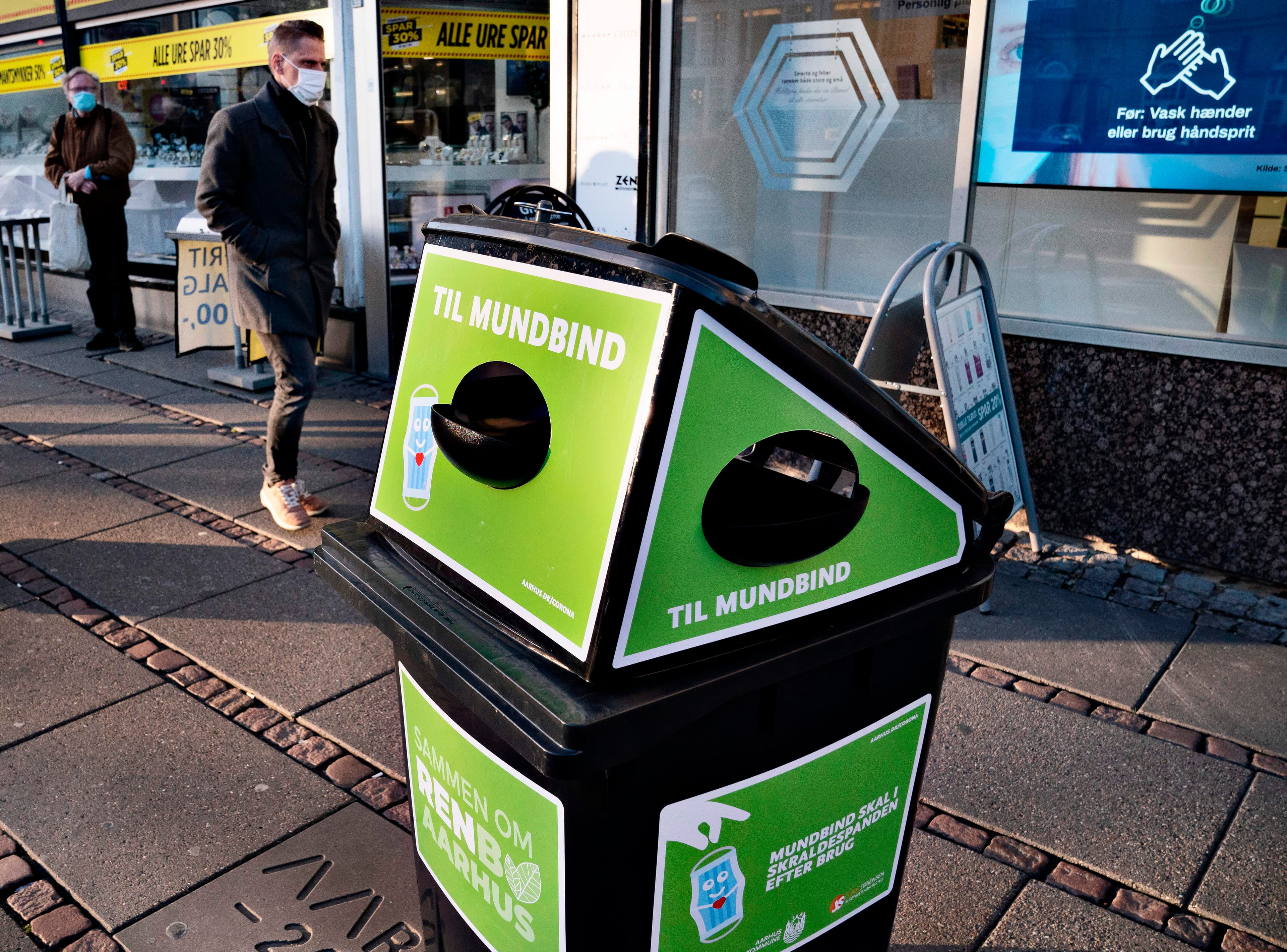 A green trash bin on a sidewalk in Denmark.