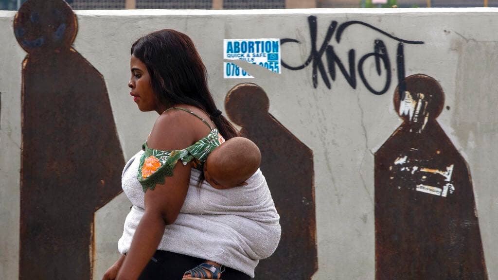People walk along a downtown street in Johannesburg, South Africa, Monday, March 16, 2020. Millions of women and girls globally have lost access to contraceptives, abortion services and related care because of the coronavirus pandemic.
