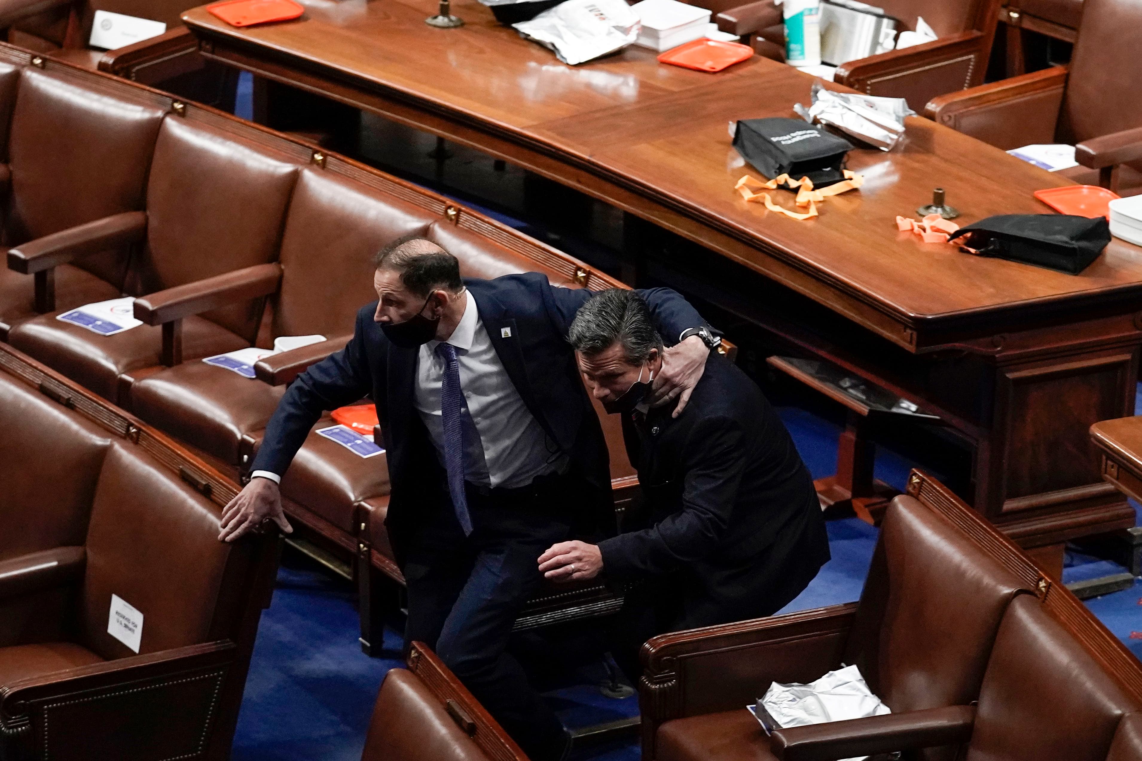 Two men in black suits run to evacuate the floor as a violent mob tries to break into the House Chamber at the US Capitol