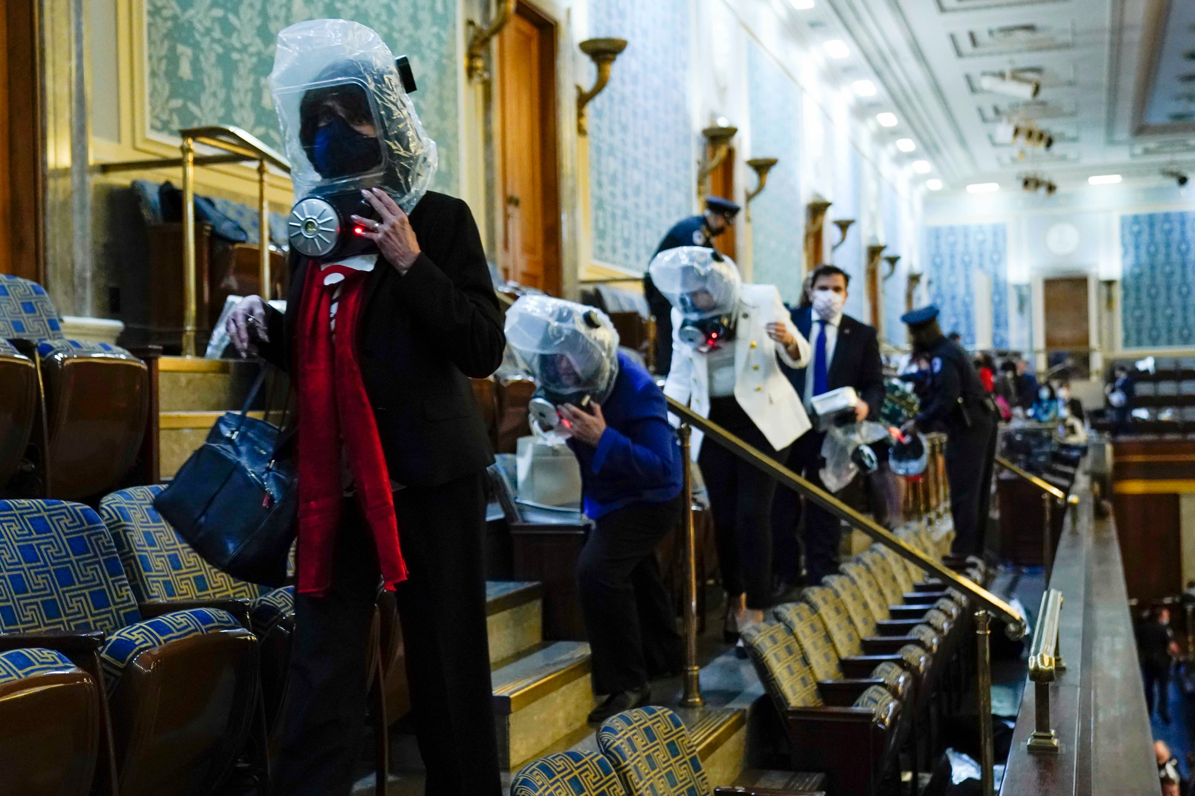 People wearing plastic protection around their heads shelter in the House gallery as a mob of Trump supporters try to break into the House chamber at the US Capitol on Wednesday, Jan. 6, 2021, in Washington, DC.