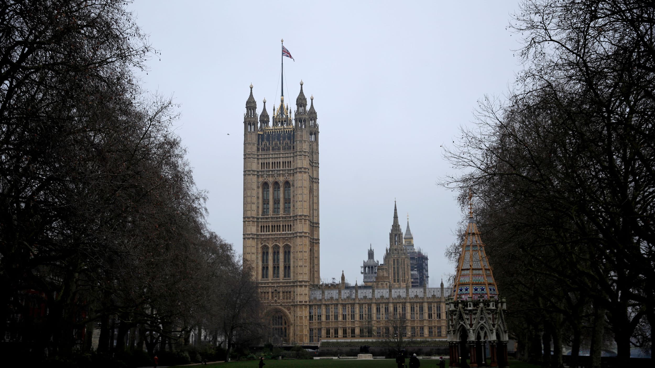 The Houses of Parliament is shown in the distance in London with trees framing the either side of the photograph.
