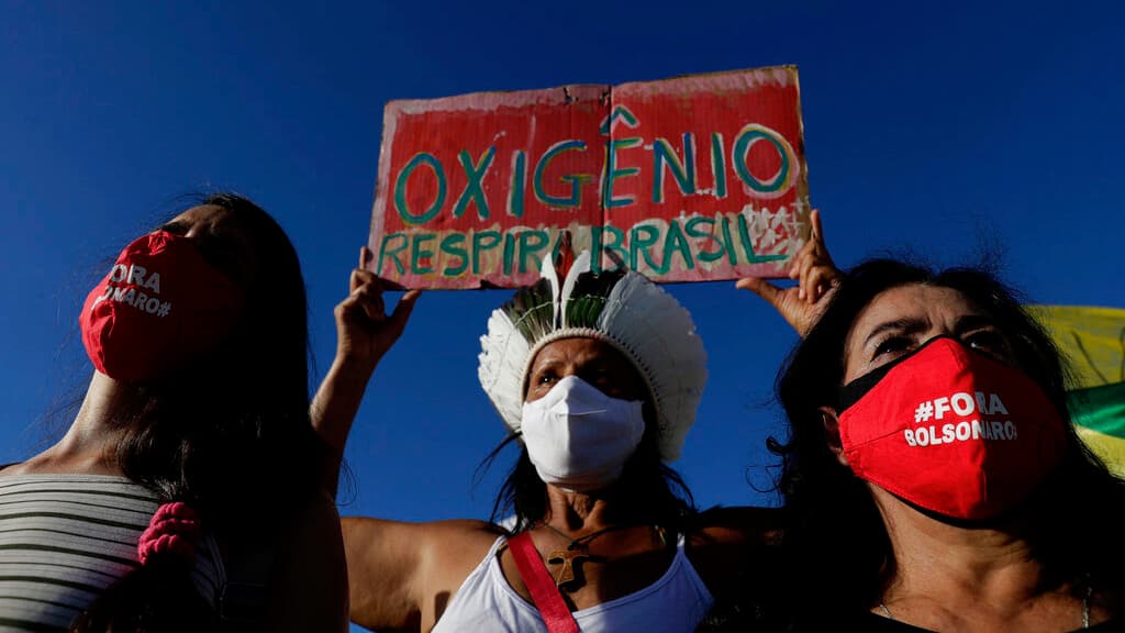 Demonstrators wearing masks with text written in Portuguese that read "Bolsonaro out," and a sign with the phrase "Oxygen, Breathe Brazil," protest against the government's response in combating COVID-19 and demanding the impeachment of Brazil's President