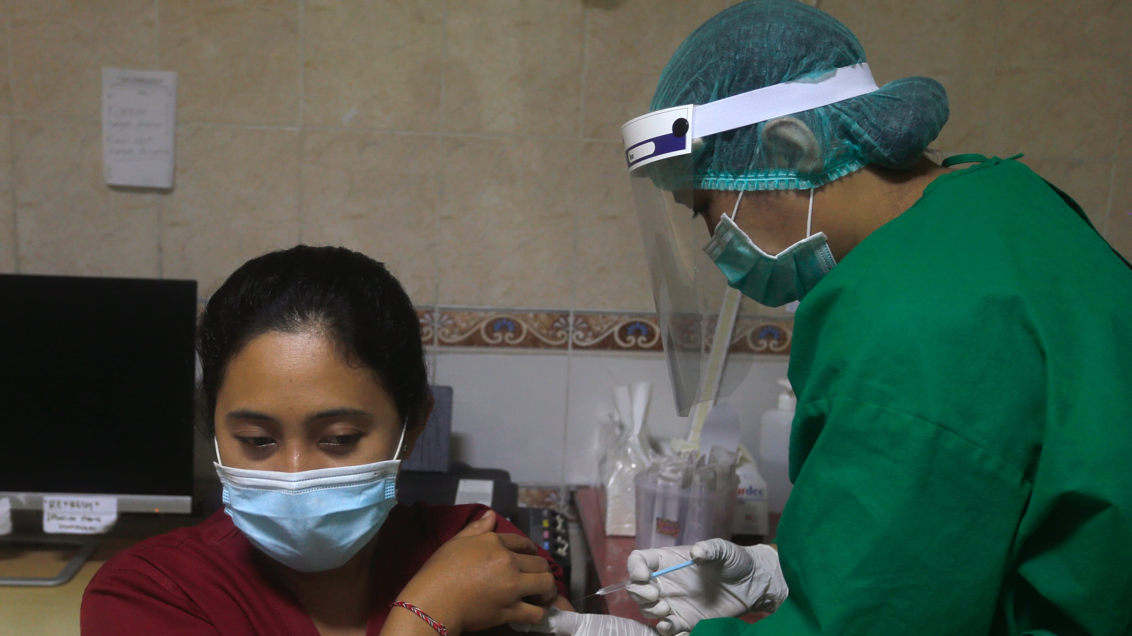 A health worker gives an injection to a mock patient during a coronavirus vaccine drill in Bali, Indonesia.