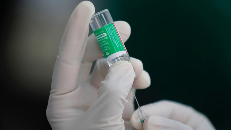A gloved hand holds a needle up-close.