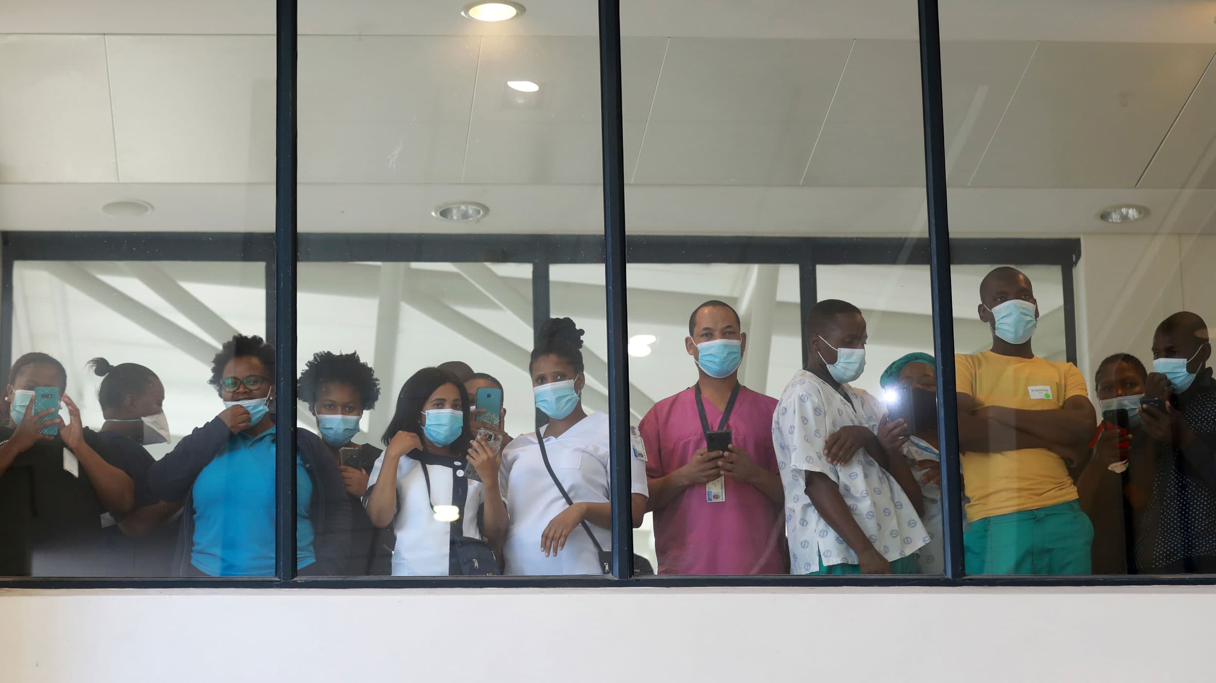 A small crowd of people are shown standing shoulder-to-shoulder, viewed through glass in a photo taken from below.
