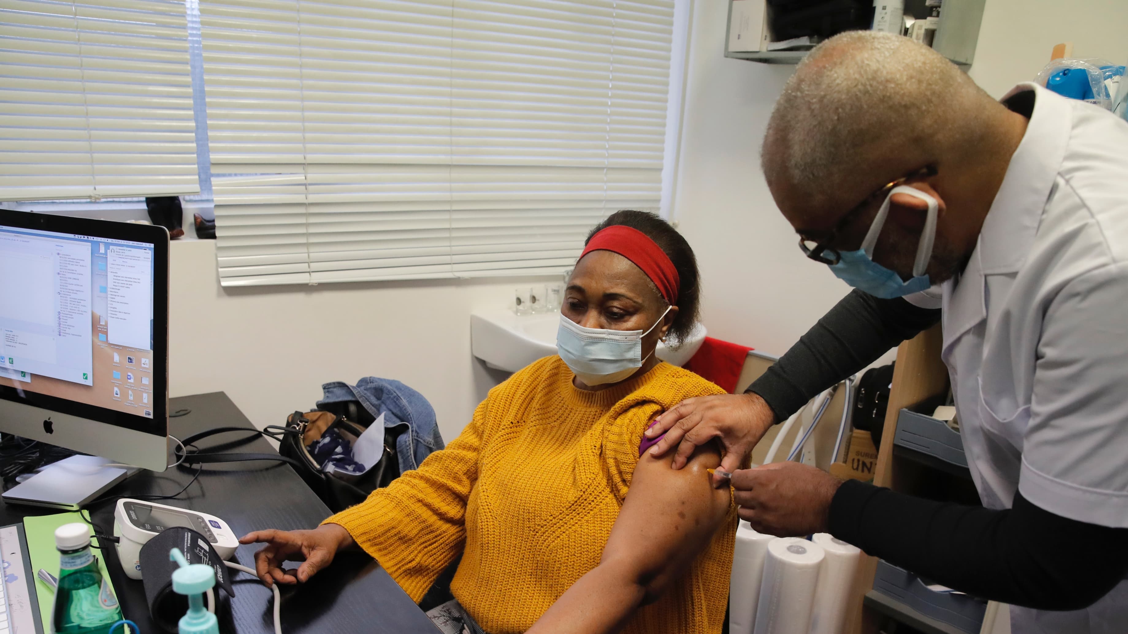 A doctor gives a patient the coronavirus vaccine in his office.