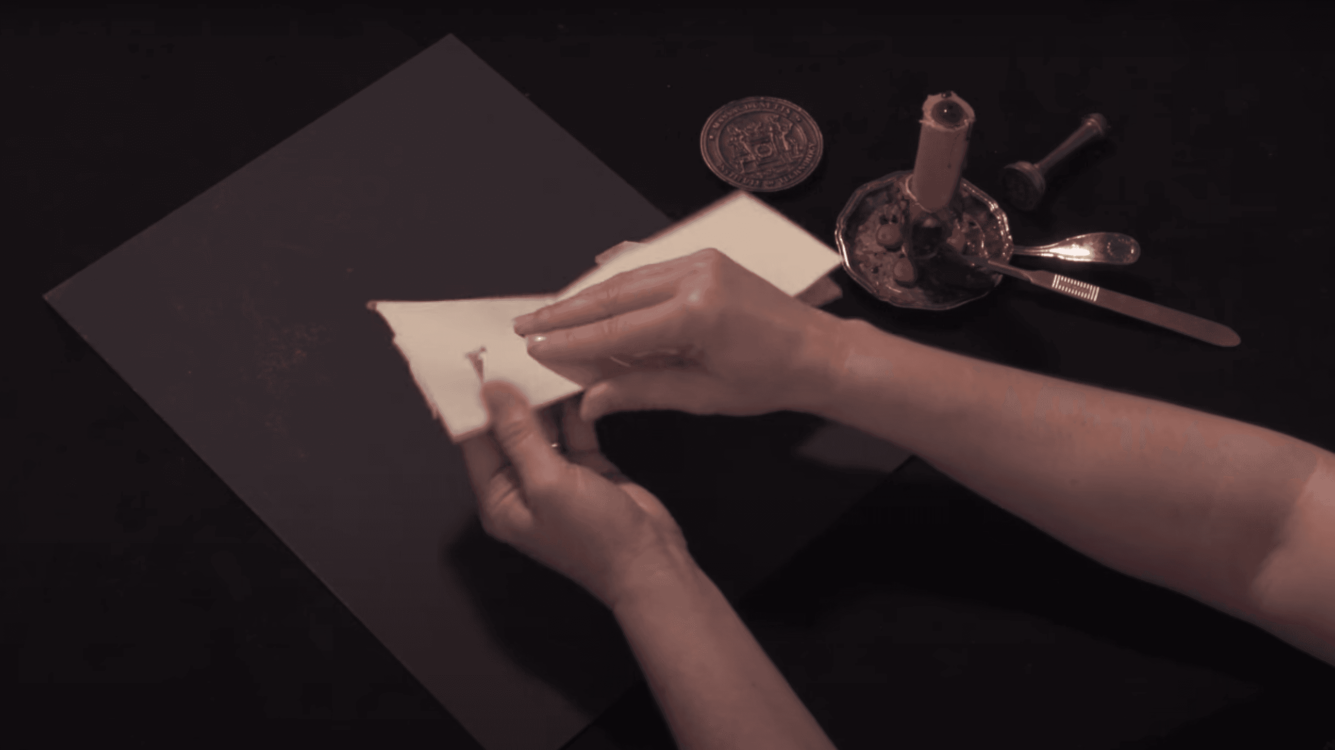 Hands fold a sheet of paper