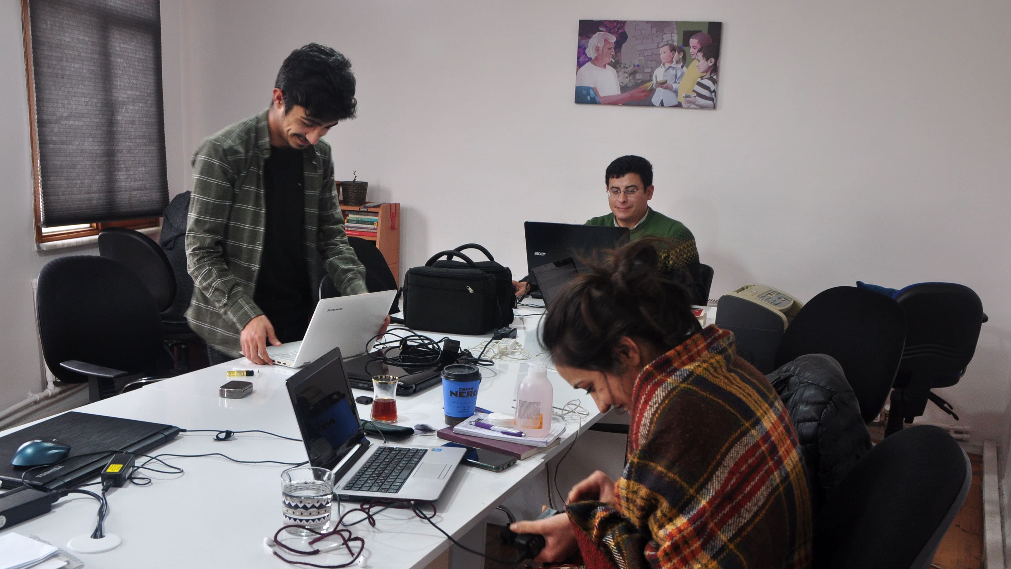 A team of journalists gather around a table with laptops