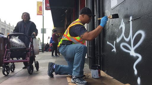 Community ambassador Sakhone Lasaphangthong helps paint a storefront in Oakland’s Chinatown. 