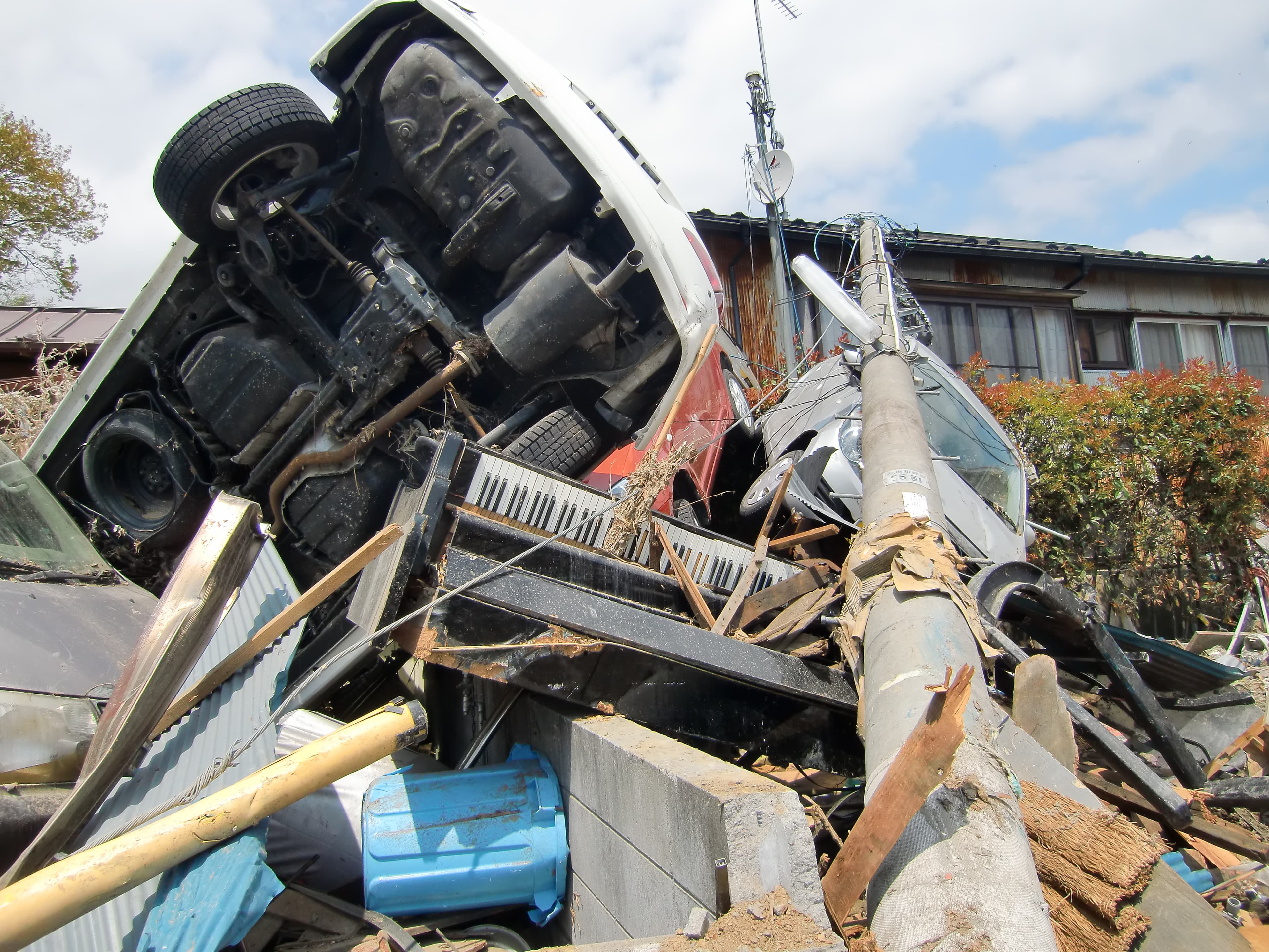 A destroyed piano is shown with a telephone pole and car on top of it.