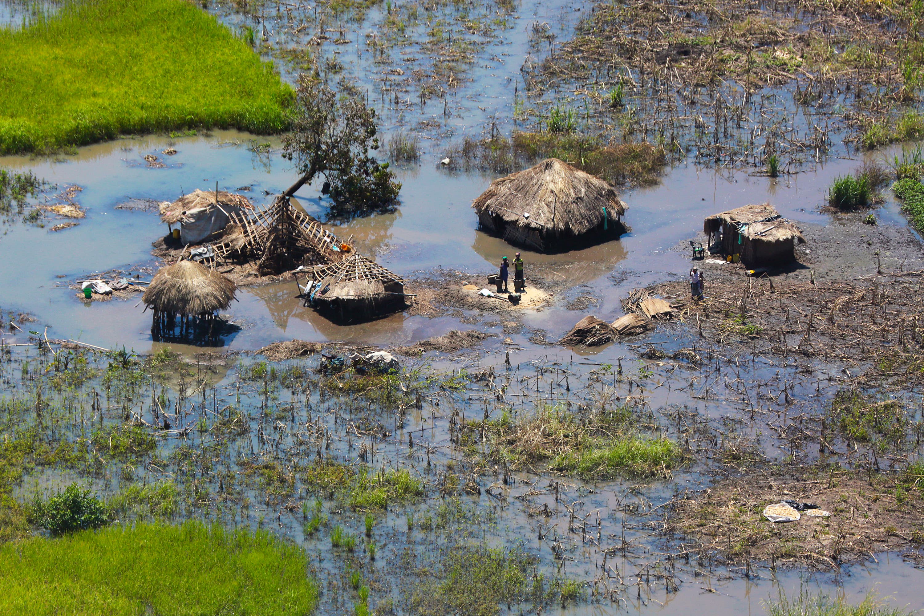 People stand outside their submerged homes near Nhamatanda, about 80 miles from Beira, in Mozambique, on March 26, 2019.