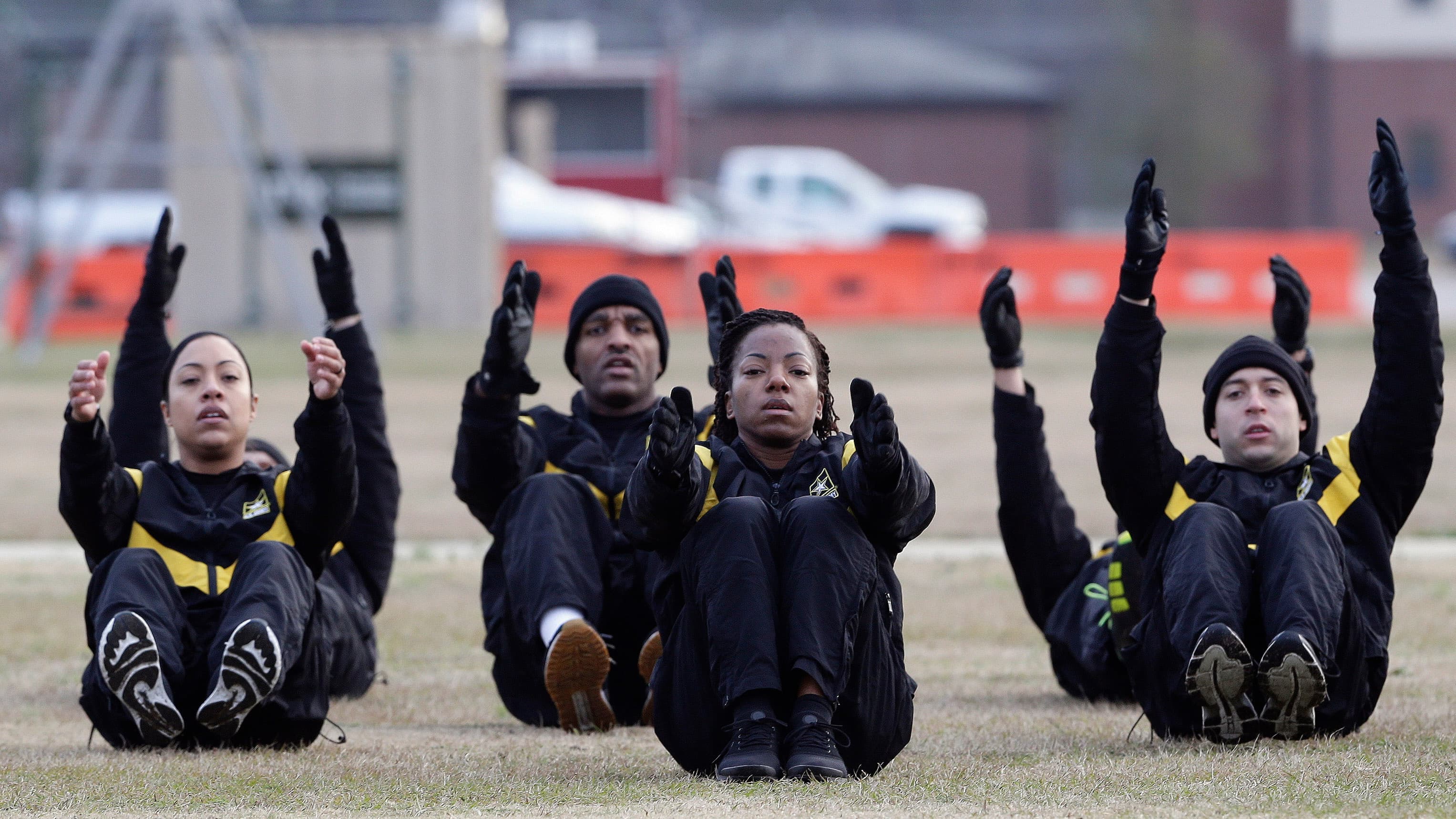 Military men and women exercise in a field.