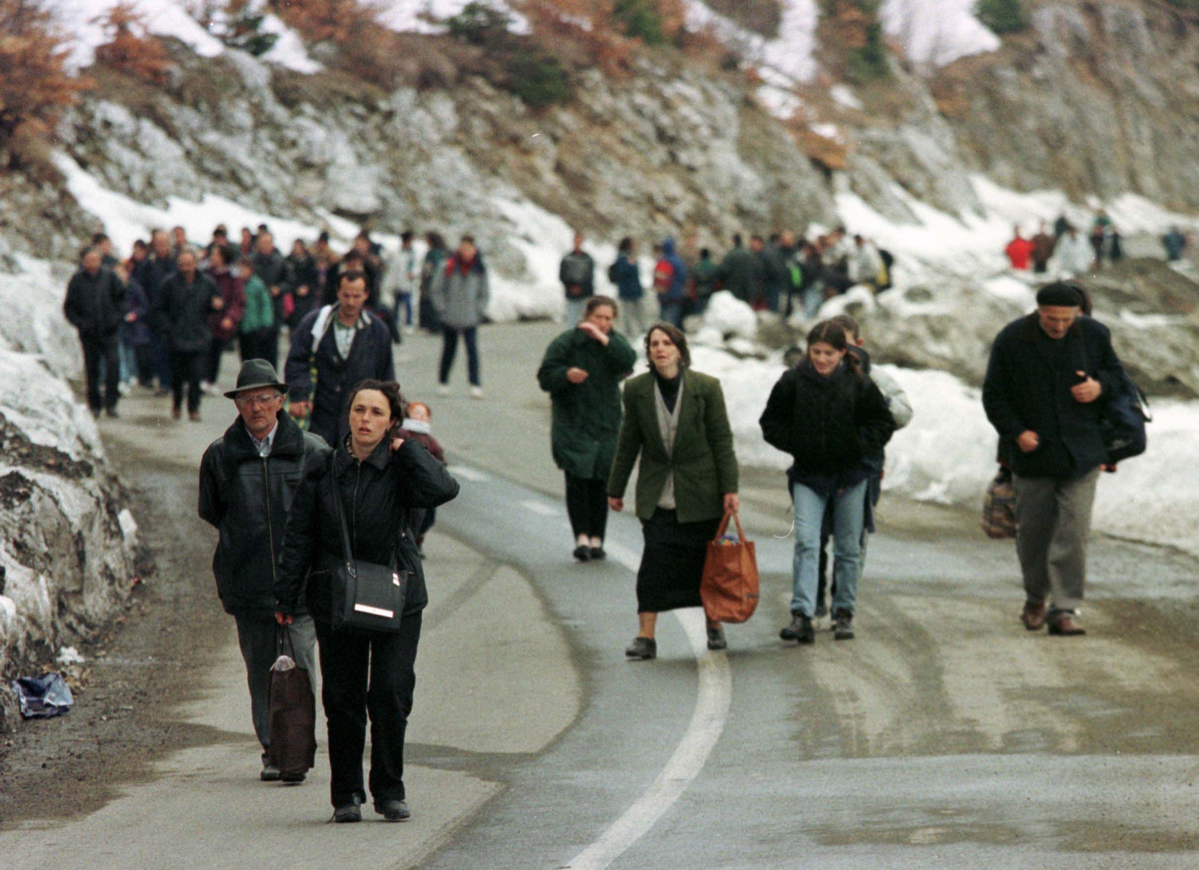 A large group of people walking on a mountainside road.