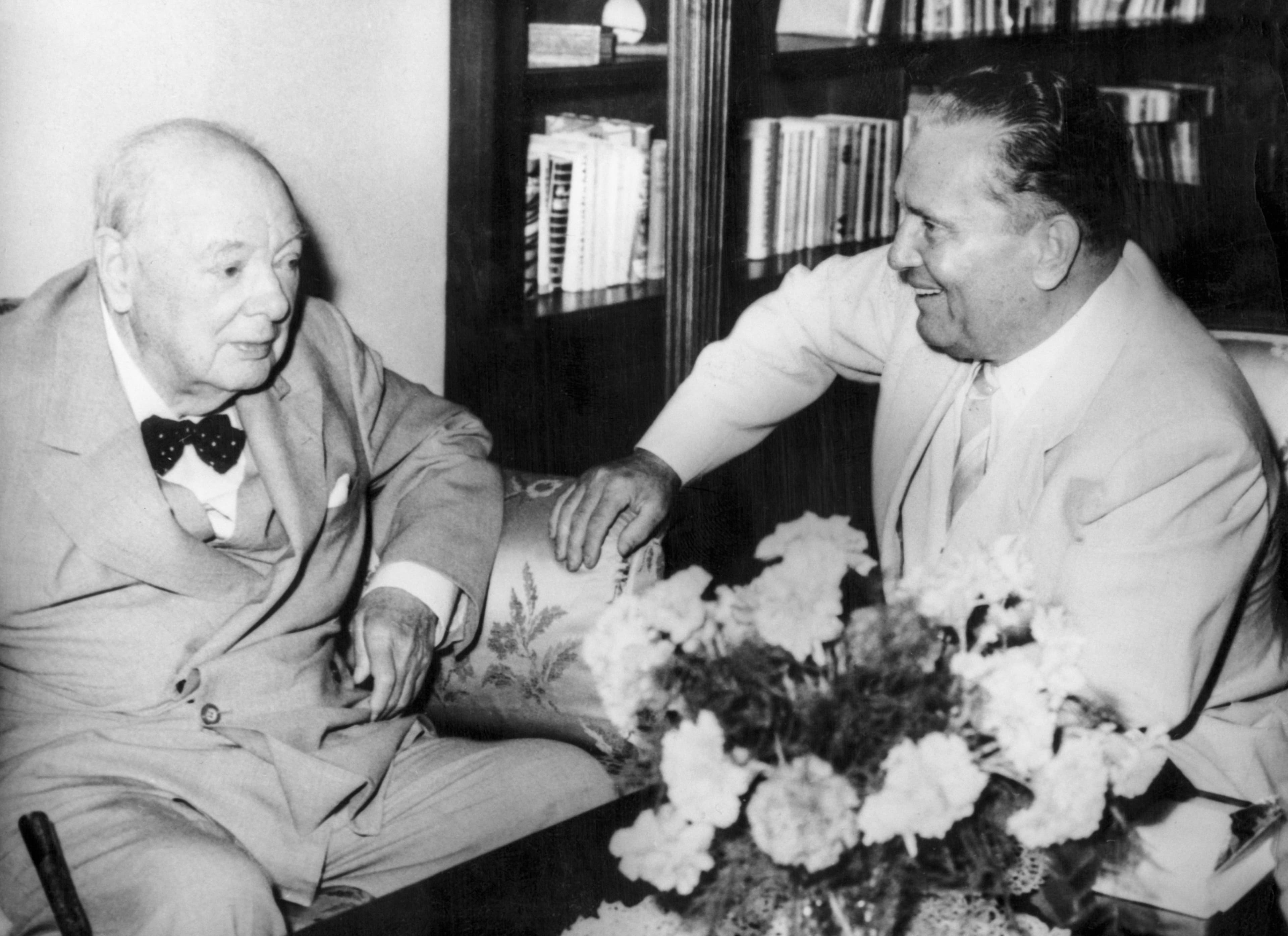 A candid photo of two men sitting next to each other and talking.
