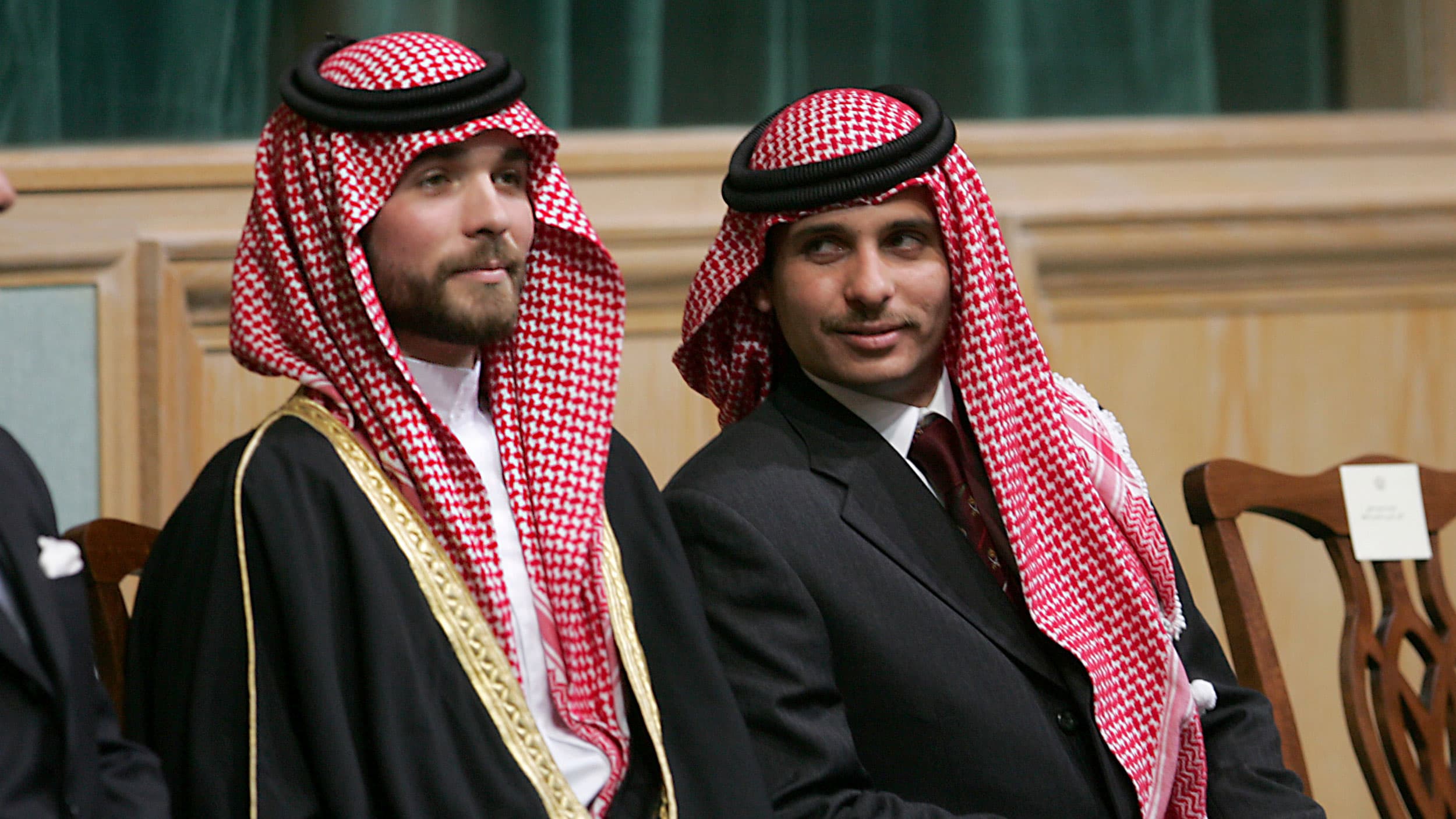 Prince Hamzah Bin Al-Hussein (R) and Prince Hashem Bin Al-Hussein (L) are shown sitting and wearing traditional red and white headscarves