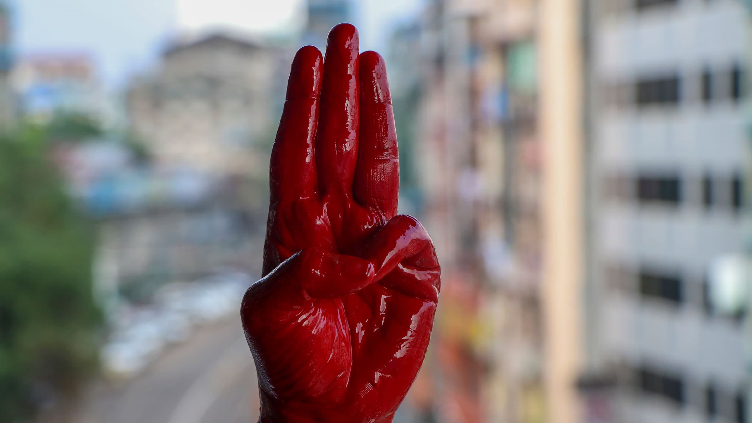 A hand painted red is depicted signing the number three.