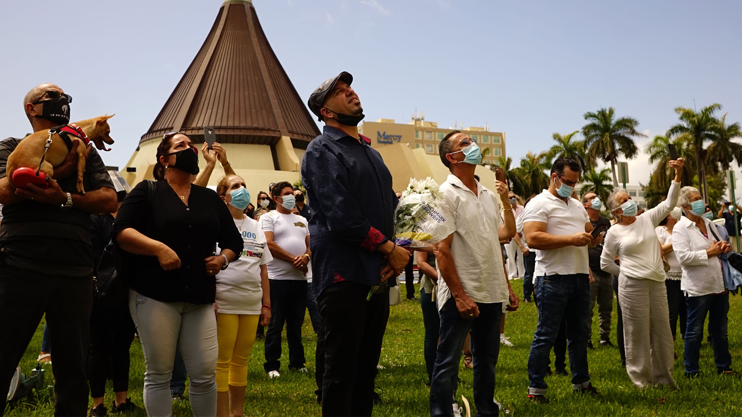 Group of people gather outside a church and look upward in prayers.