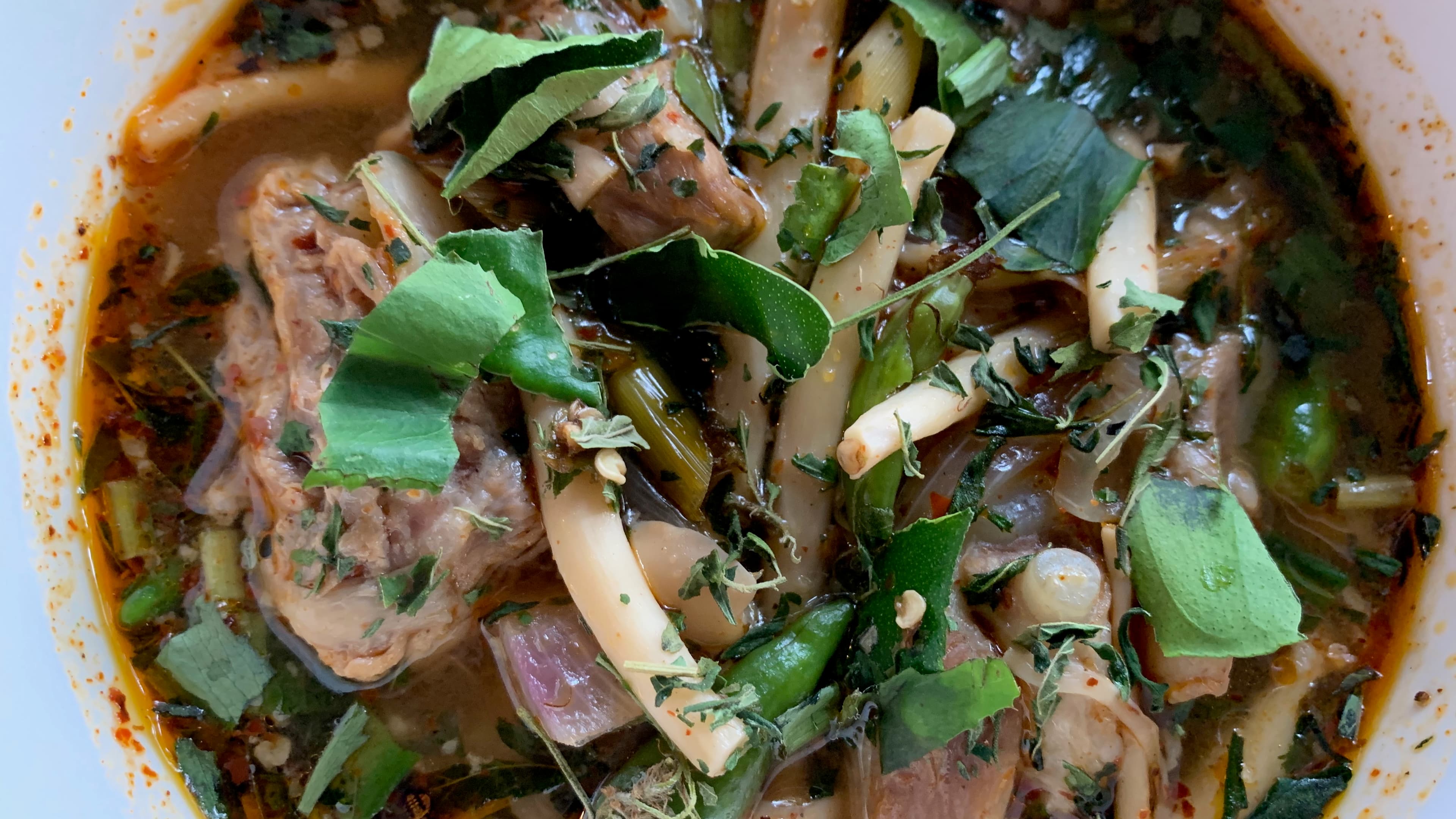 Sour pork soup flecked with cannabis leaves, served at Baan Lao Ruang restaurant in Thailand.