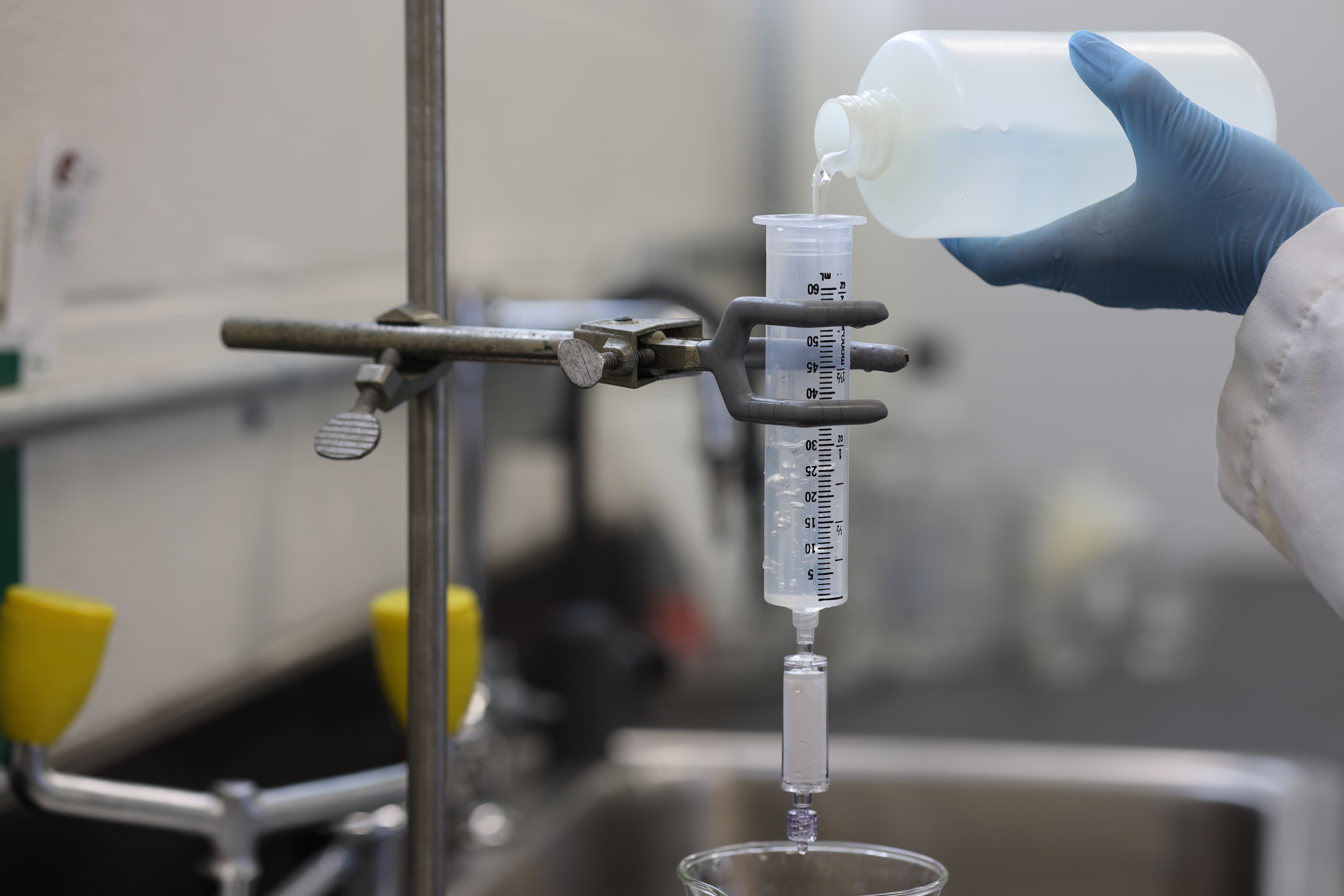 A hand pours liquid into a tube in a medical lab
