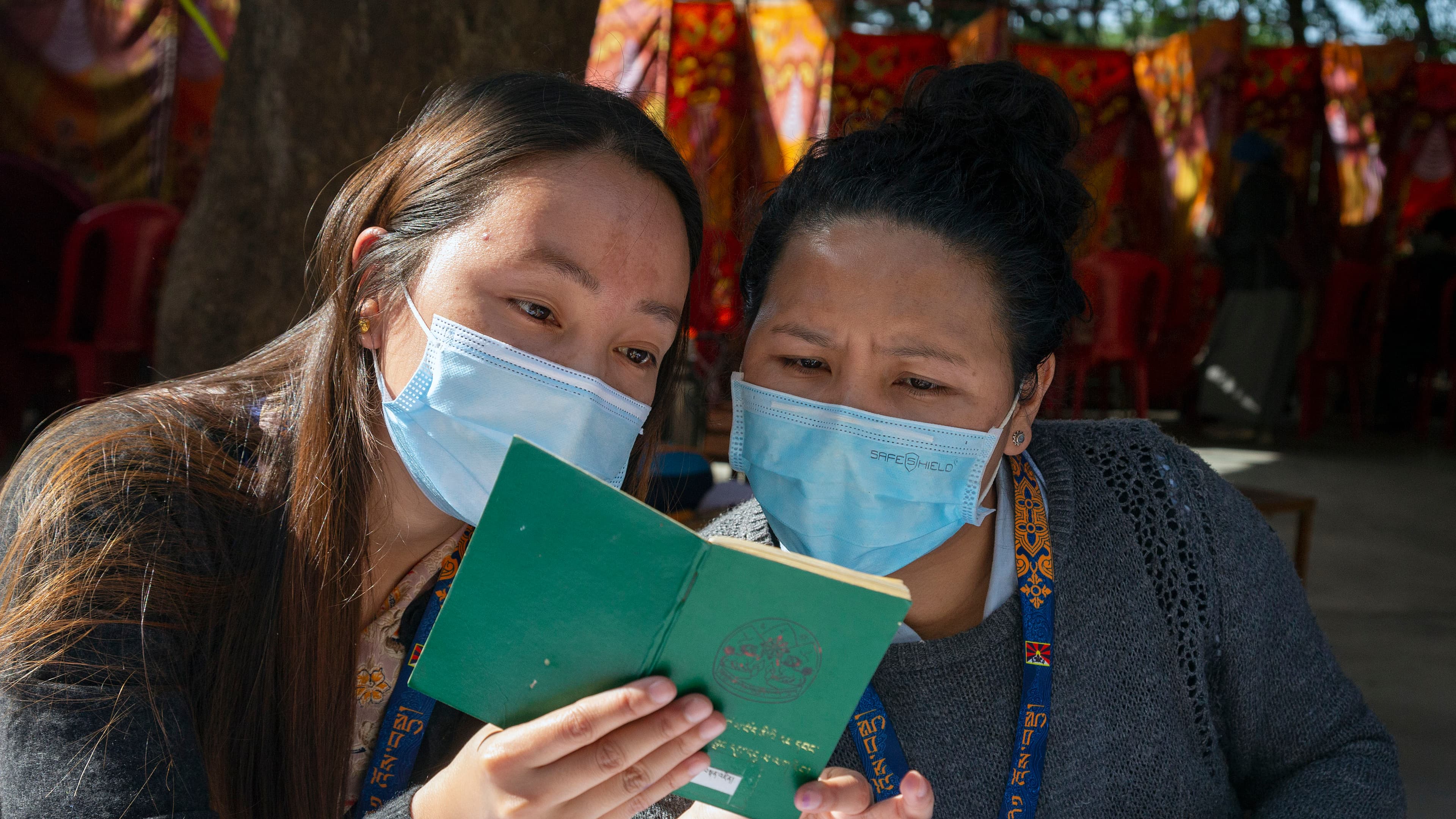 Exile Tibetan booth officials look at a green book, a necessary document for Tibetans to vote, during the second and final round of voting to elect their parliamentarians and the leader of the Central Tibetan Administration