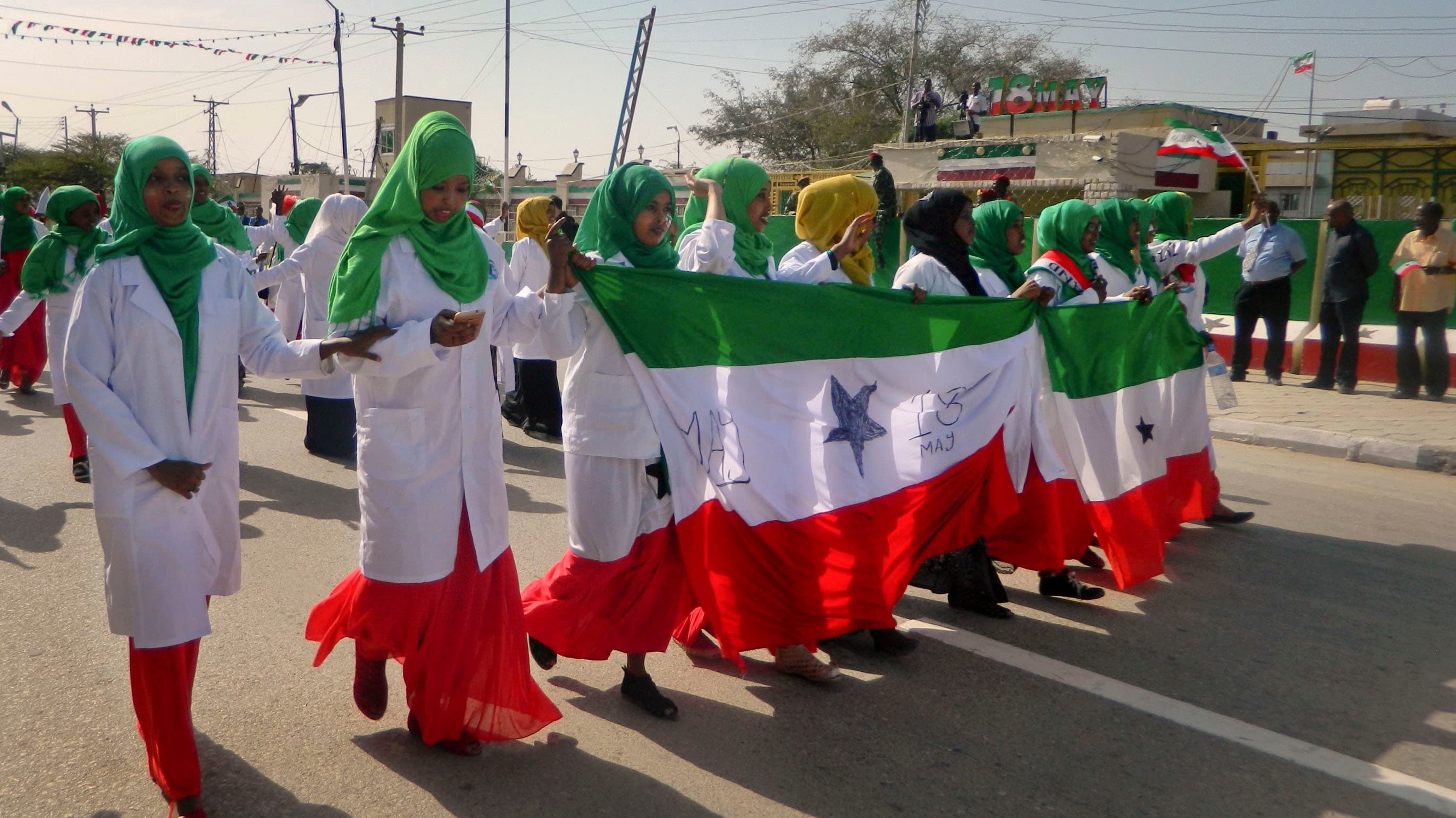 Women wear red, white, and green clothes and march in a parade celebrating independence.