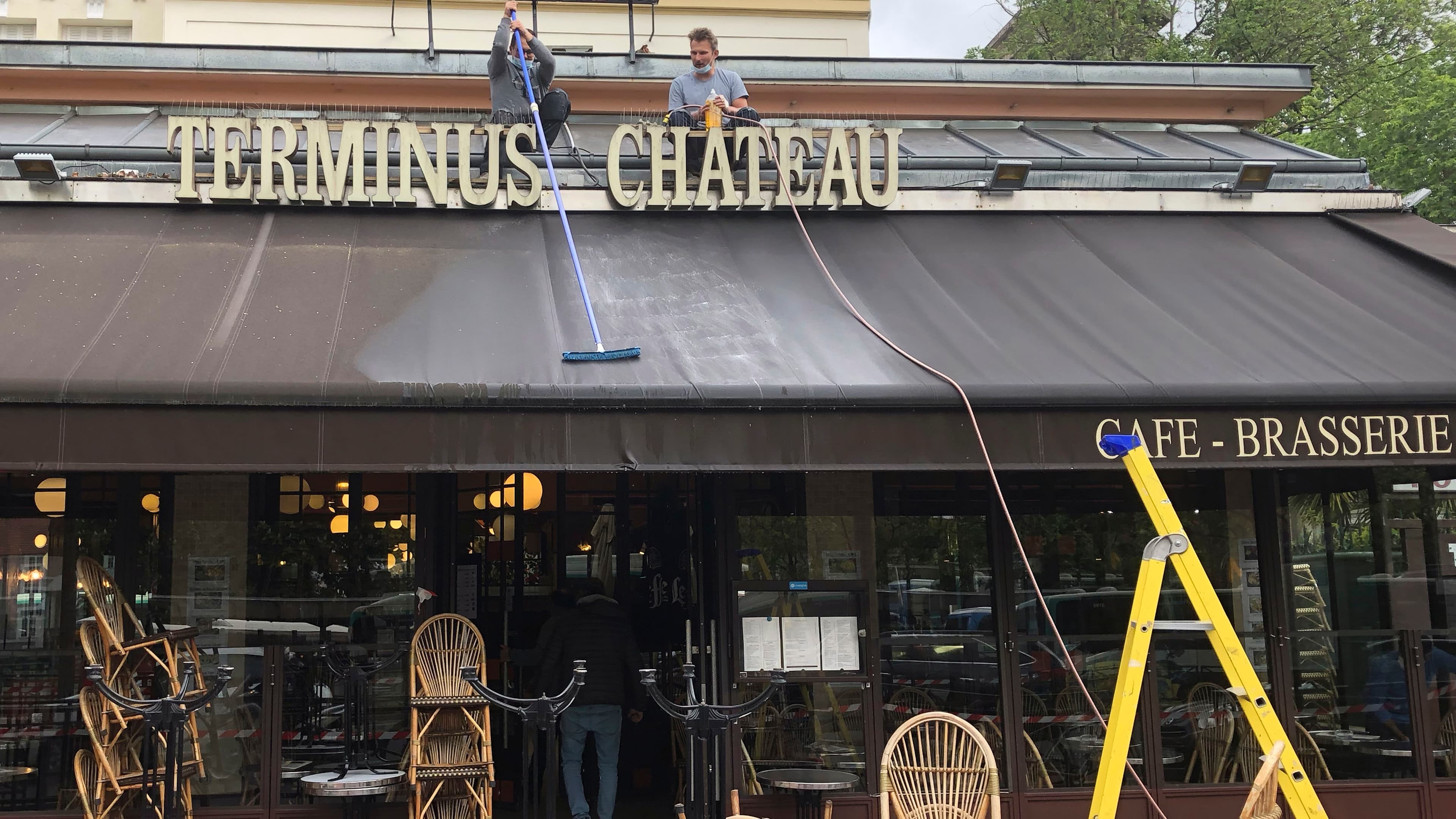 Restaurant workers clean the awning of a restaurant near Chateau de Vincennes.
