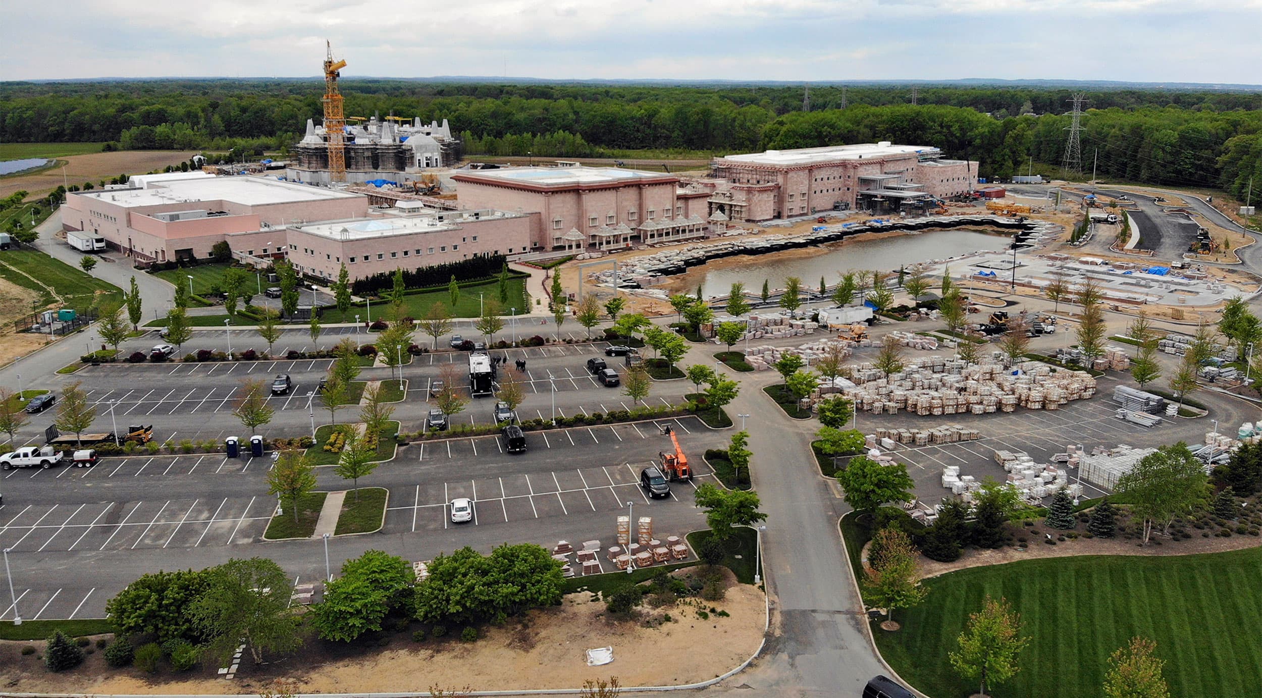 Aerial view of a Hindu temple next to a parking lot and greenery.