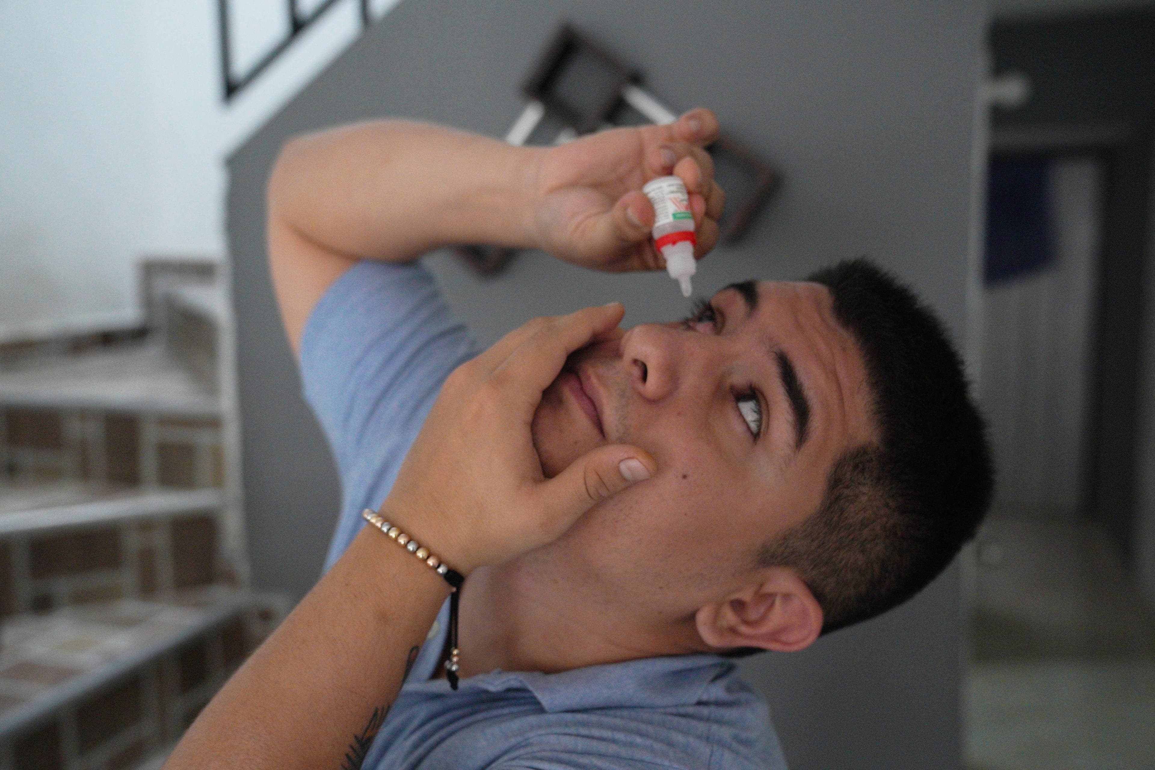 Camilo Suarez places droplets in his right eye to reduce inflammation. Suarez was hit with a rubber bullet during a vigil on May 2, and lost most of his sight in that eye.