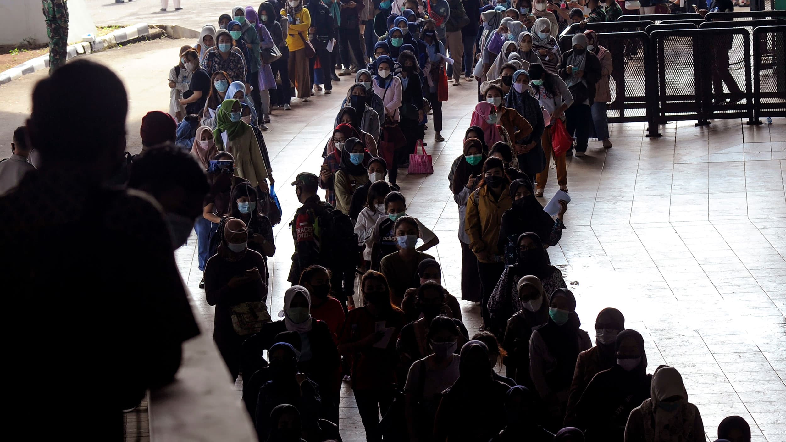 Three long lines are shown with hundreds of people standing and waiting.