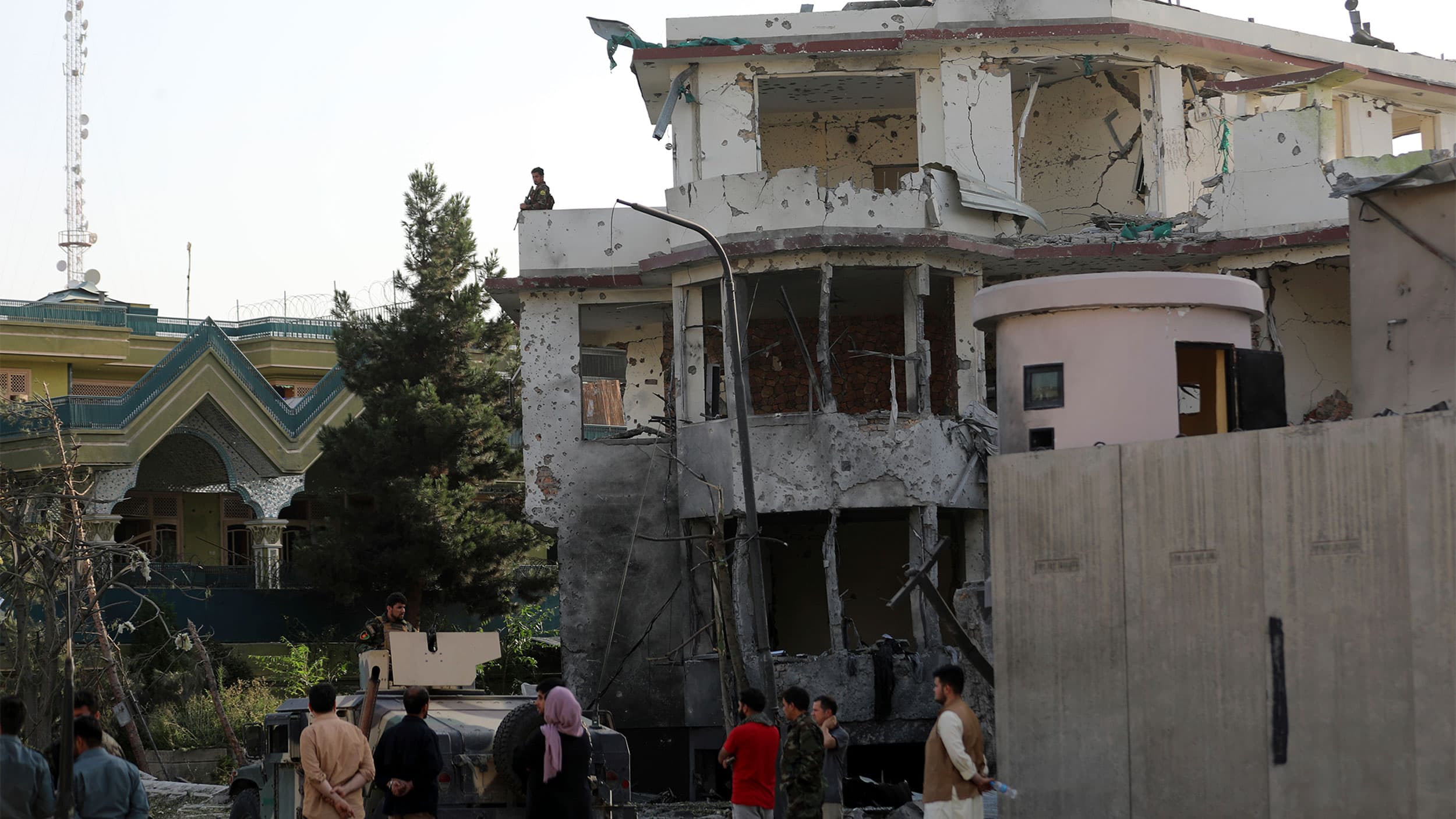 People stand around a bombed-out building