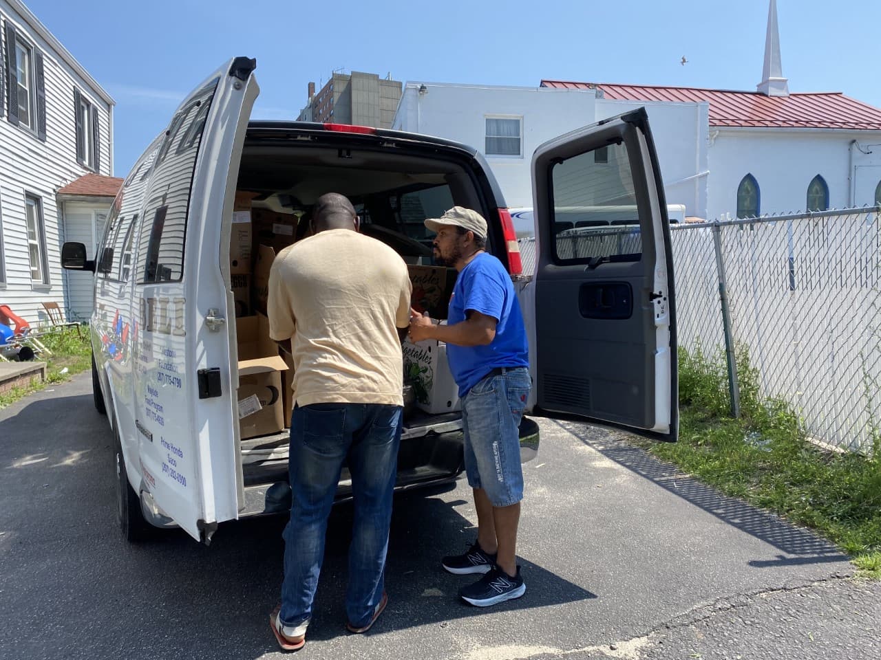 Rui Pires, right, speaks with a member of the Angolan community during his food delivery route in Portland, Maine