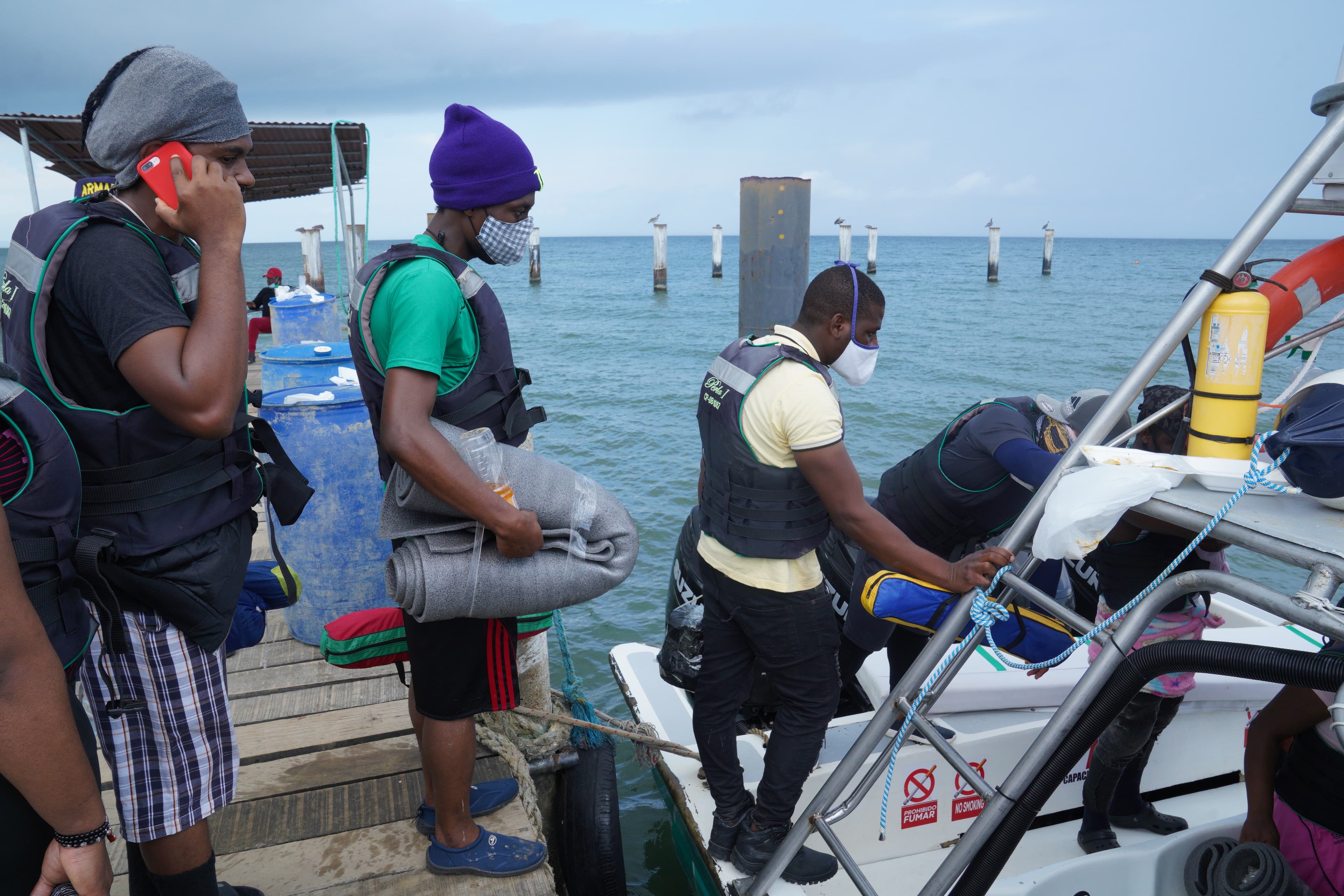 A group of Haitian migrants boards a boat that will take them from Necocli, Colombia to the village of Capurgana, where the trail through the Darien Gap begins.