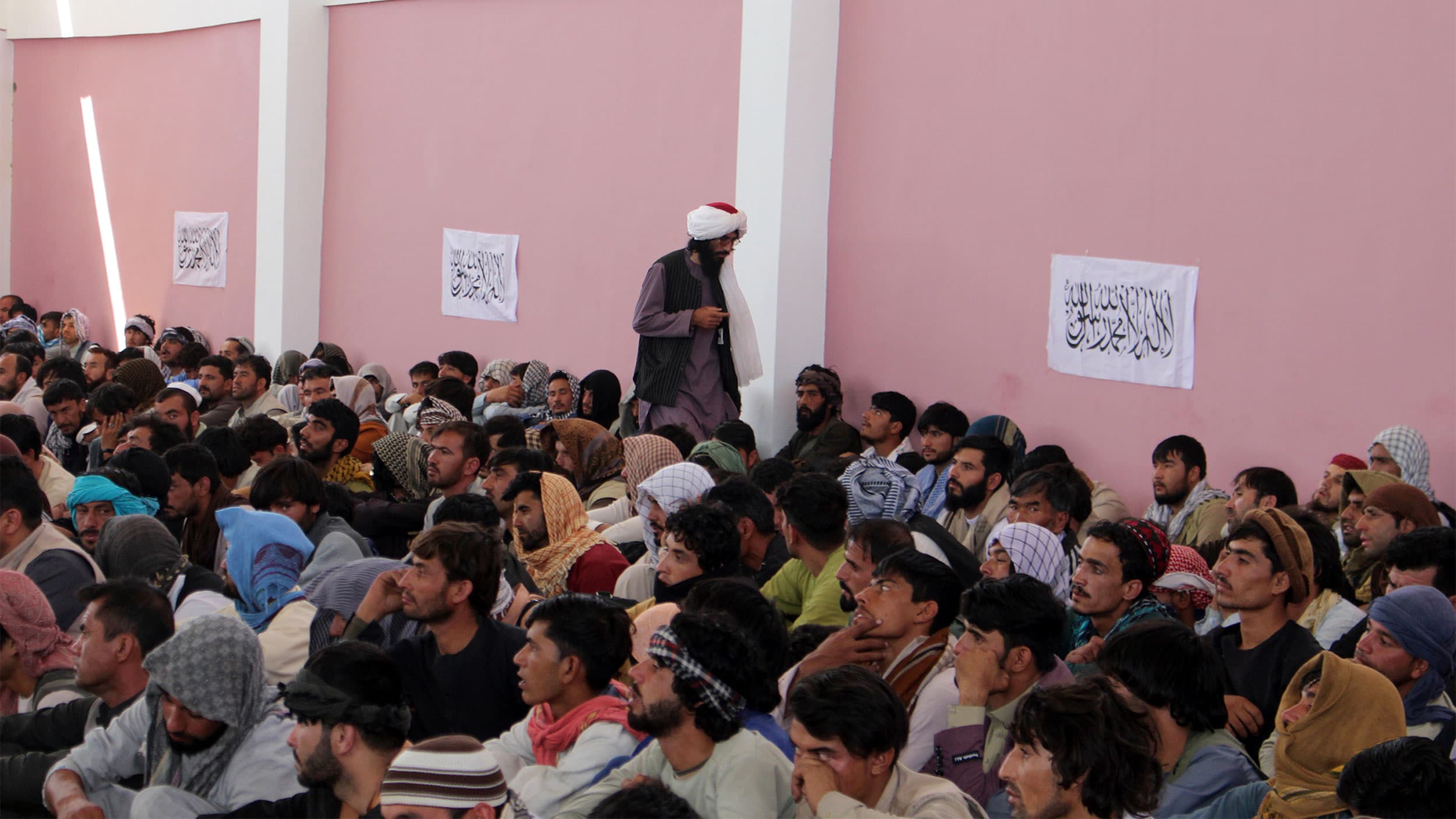 A Taliban fighter stands guard over surrendered Afghan security members forces