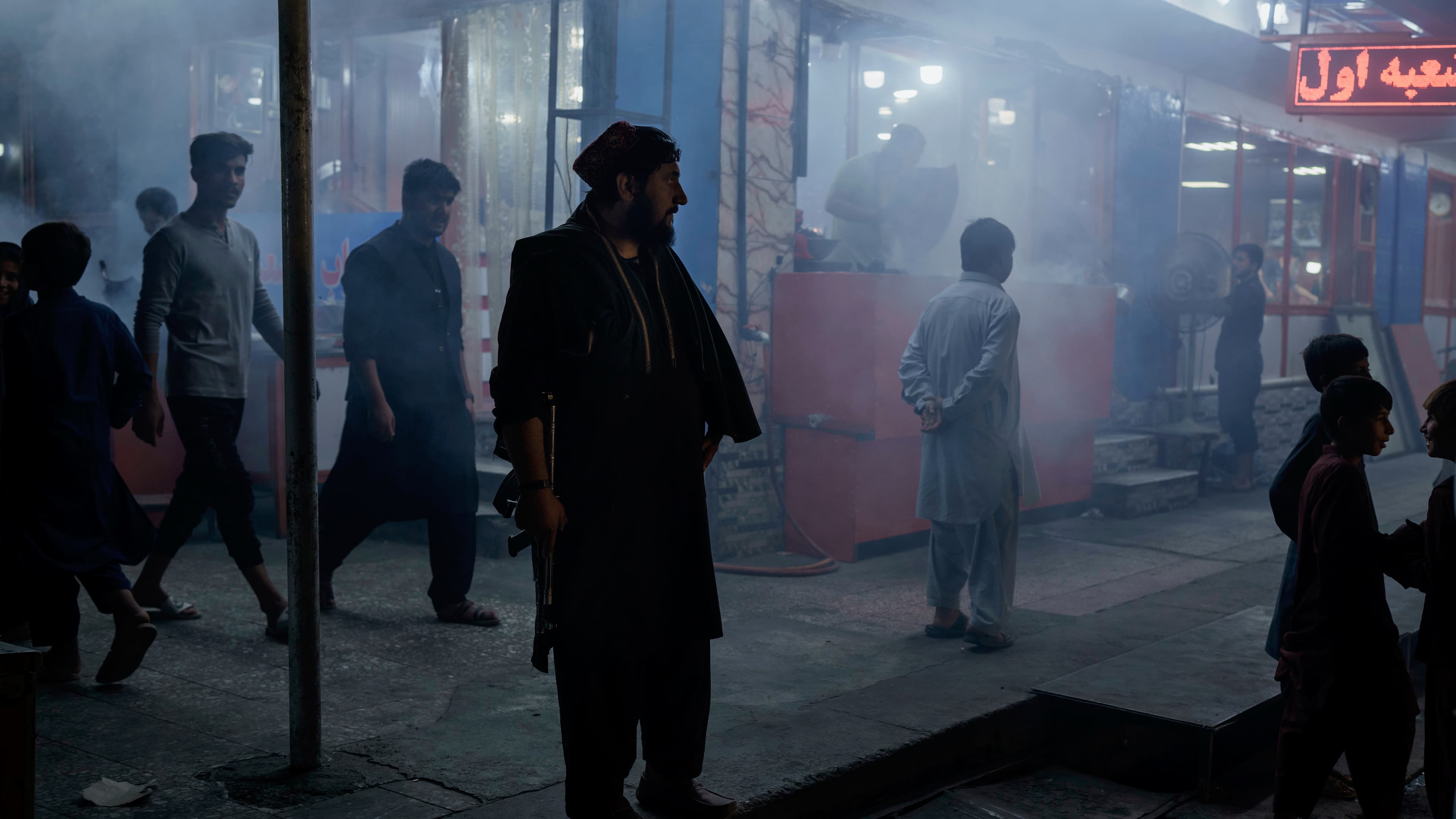 A Taliban fighter stands in the corner of a busy street at night in Kabul, Afghanistan, Sept. 17, 2021.