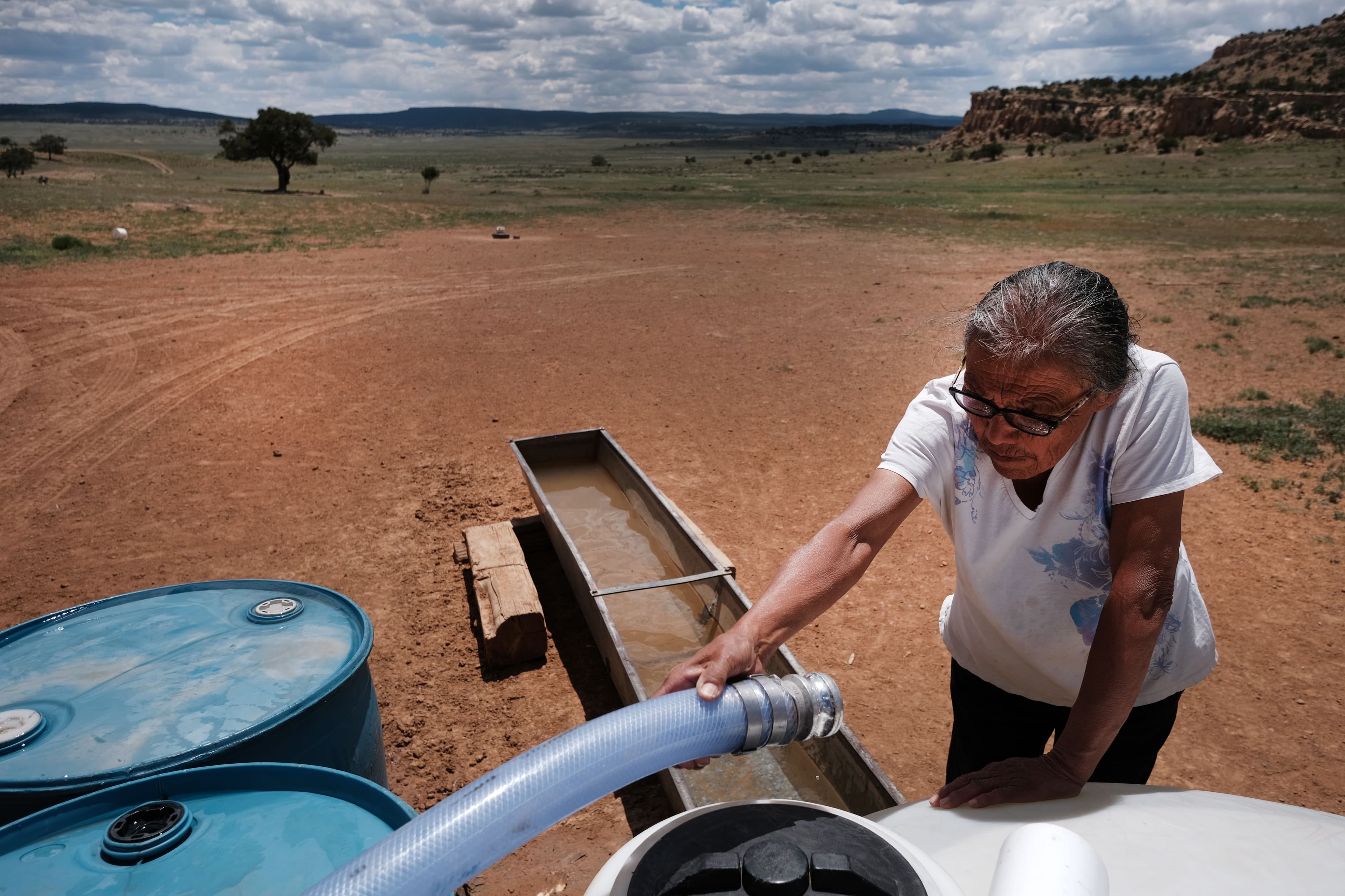 Woman holding hose from truck to fill water trough