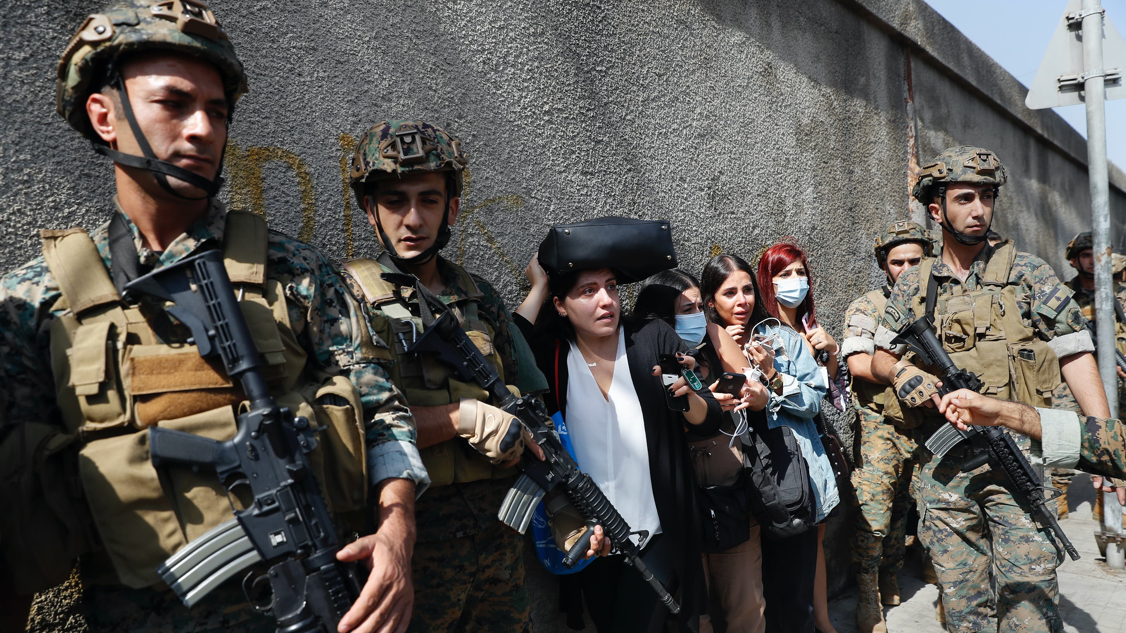 Lebanese teachers react to the sounds from nearby armed clashes as they flee their school under the protection of Lebanese soldiers after a clash erupted along a former 1975-90 civil war front line between Muslim Shiite and Christian areas at Ain el-Ruman