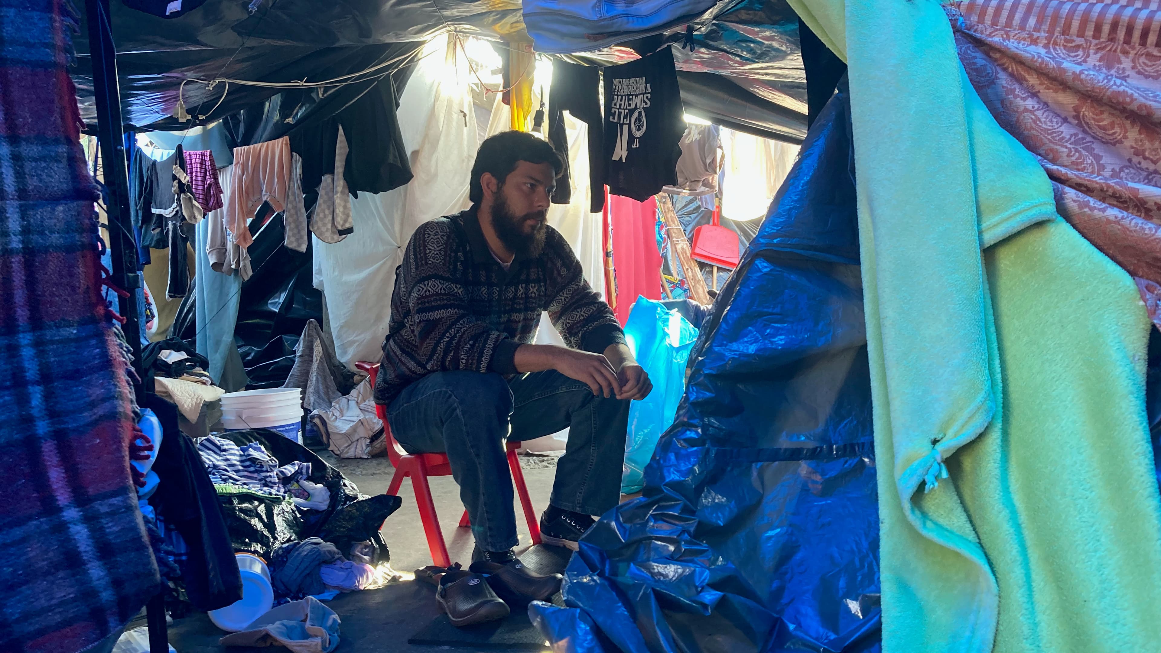 Psychologist Sebastián Farías speaks with asylum-seekers inside a migrant encampment on Nov. 6, 2021. 