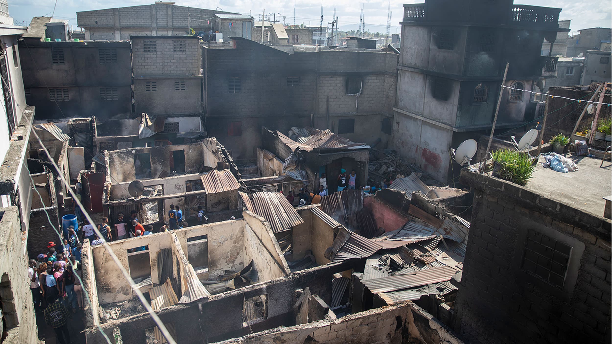 Residents stand amid their homes damaged by a gasoline truck that overturned and exploded in Cap-Haitien, Haiti