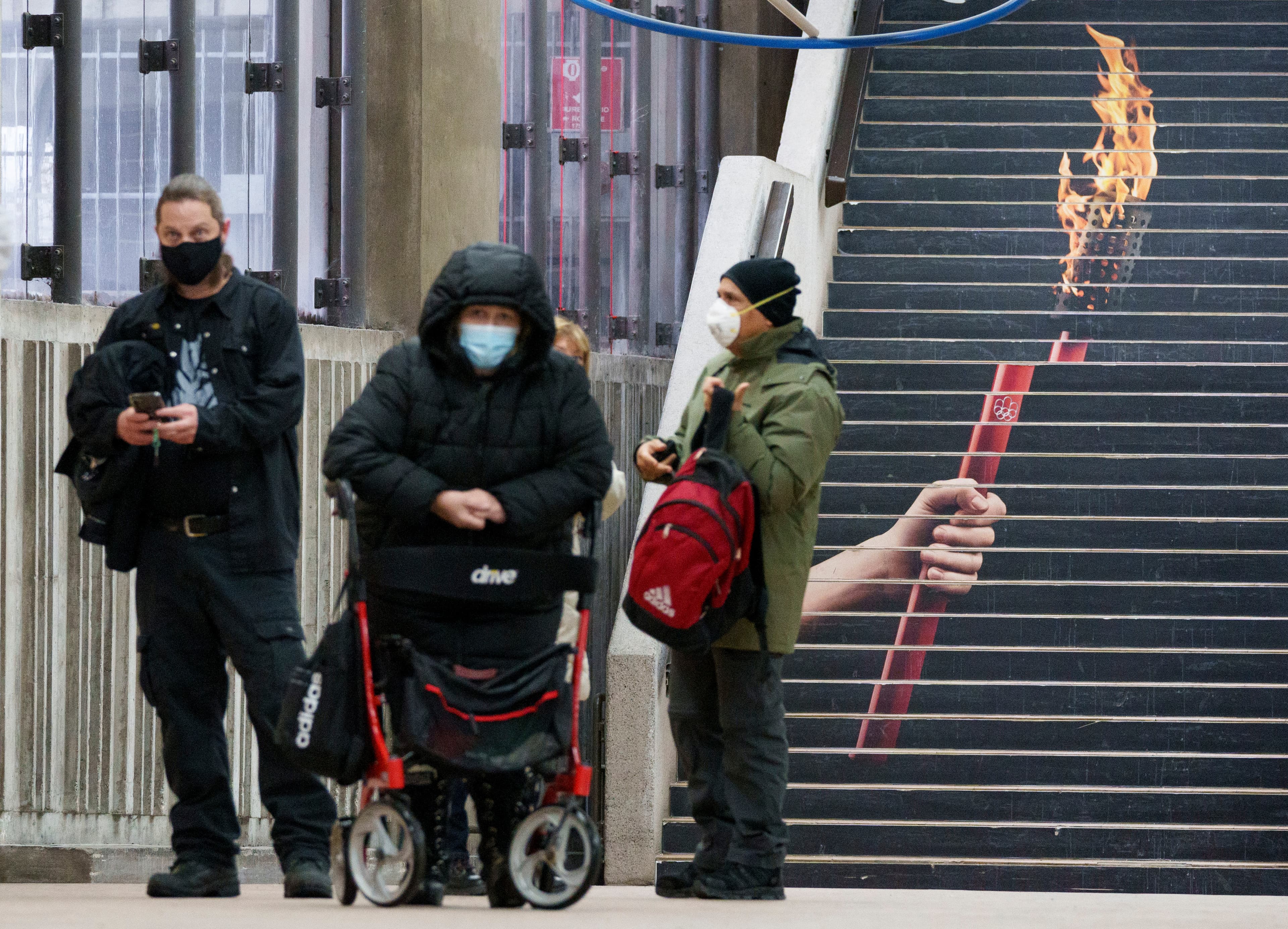 People line up to enter a COVID-19 vaccination clinic with a torch of the 1976 Montreal Summer Olympics painted on the staircase in Montreal, Jan. 6, 2022.