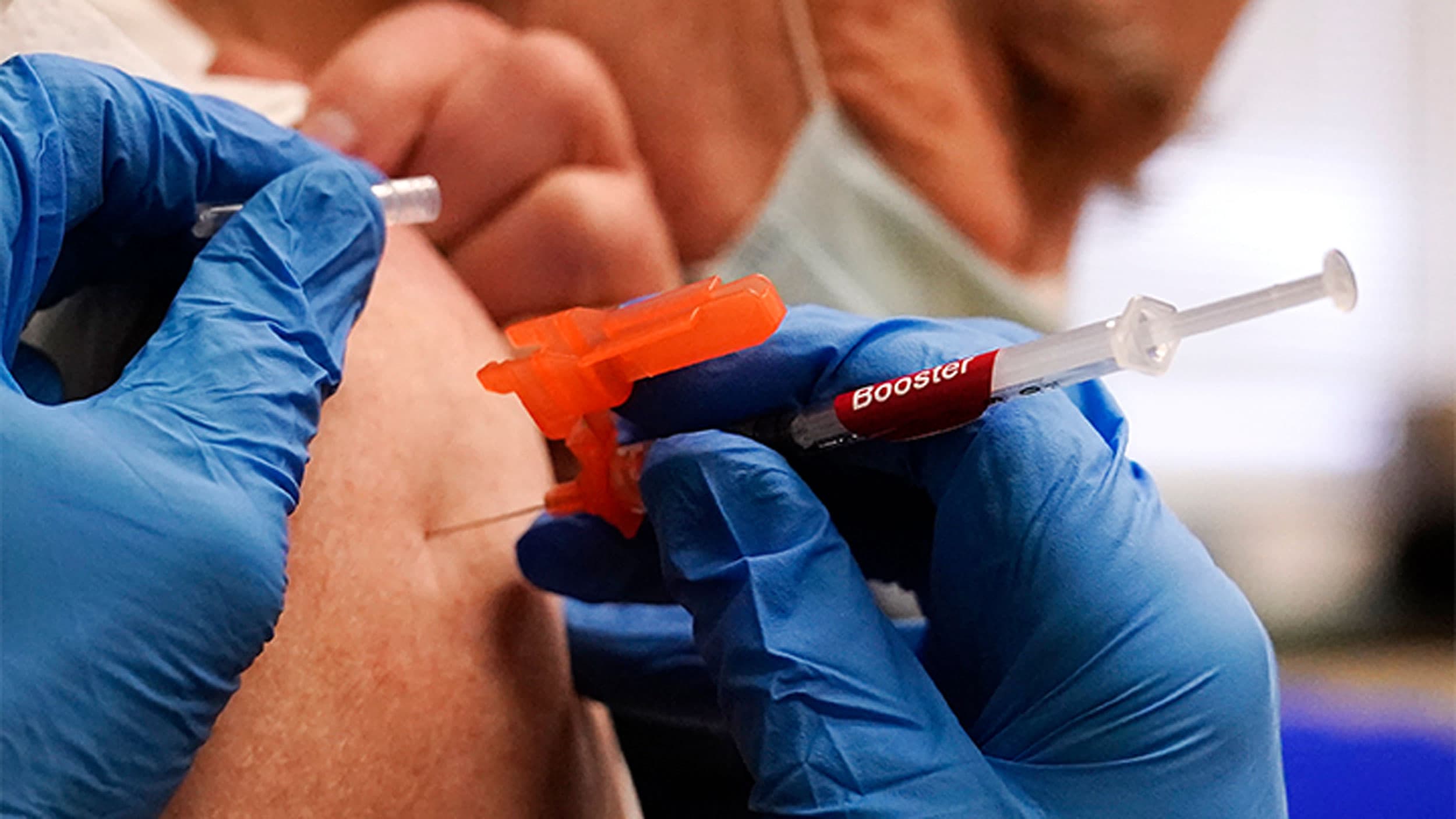 Pharmacist Kenni Clark injects Robert Champion, of Lawrence, Mass., with a booster dosage of the Moderna COVID-19 vaccine during a vaccination clinic at City of Lawrence's "The Center," which serves seniors, families and the community