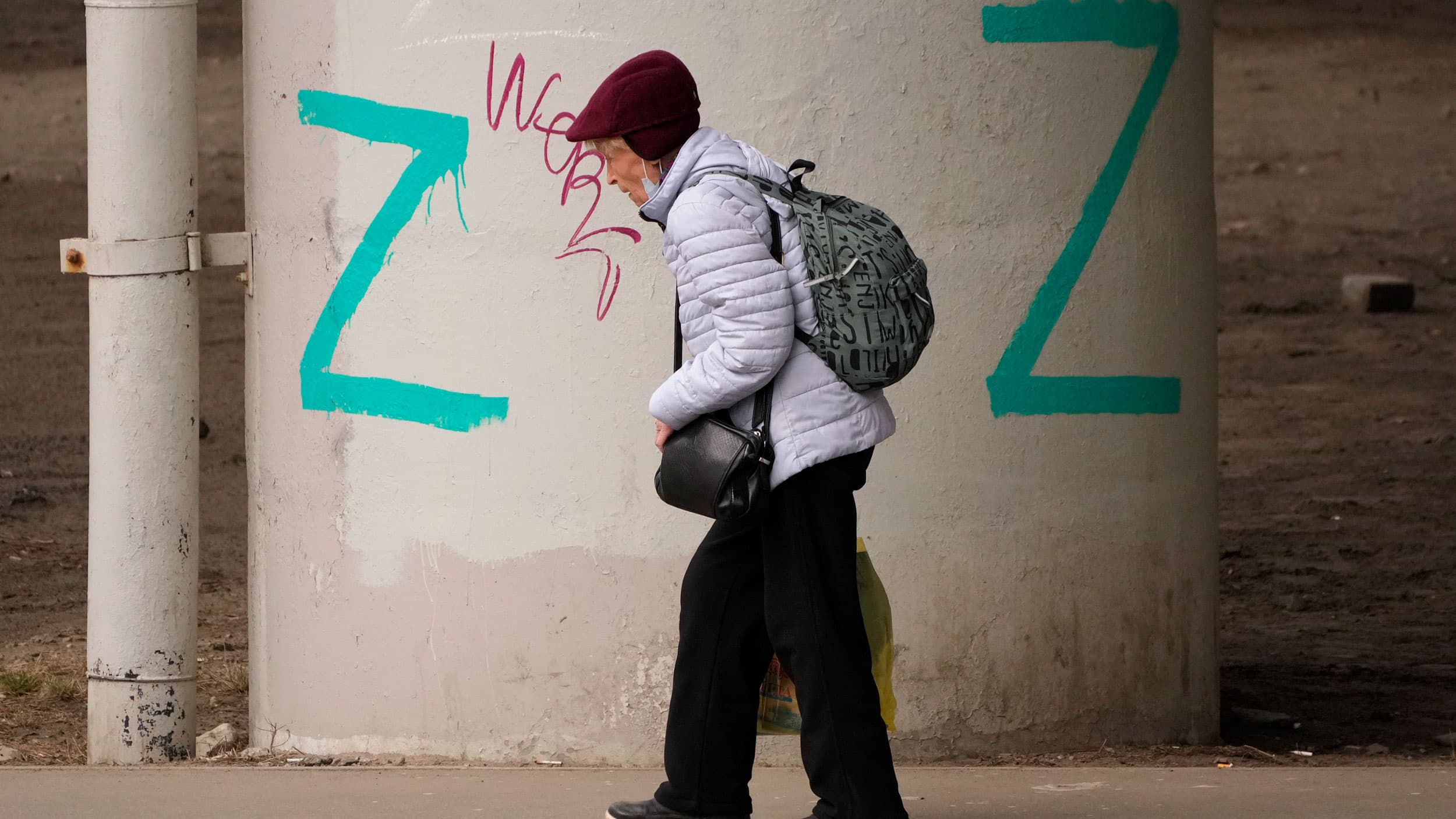 A woman walks past painted letter Z's, which has become a symbol of the Russian military, on bridge piers in St. Petersburg, Russia, Friday, April 15, 2022. 