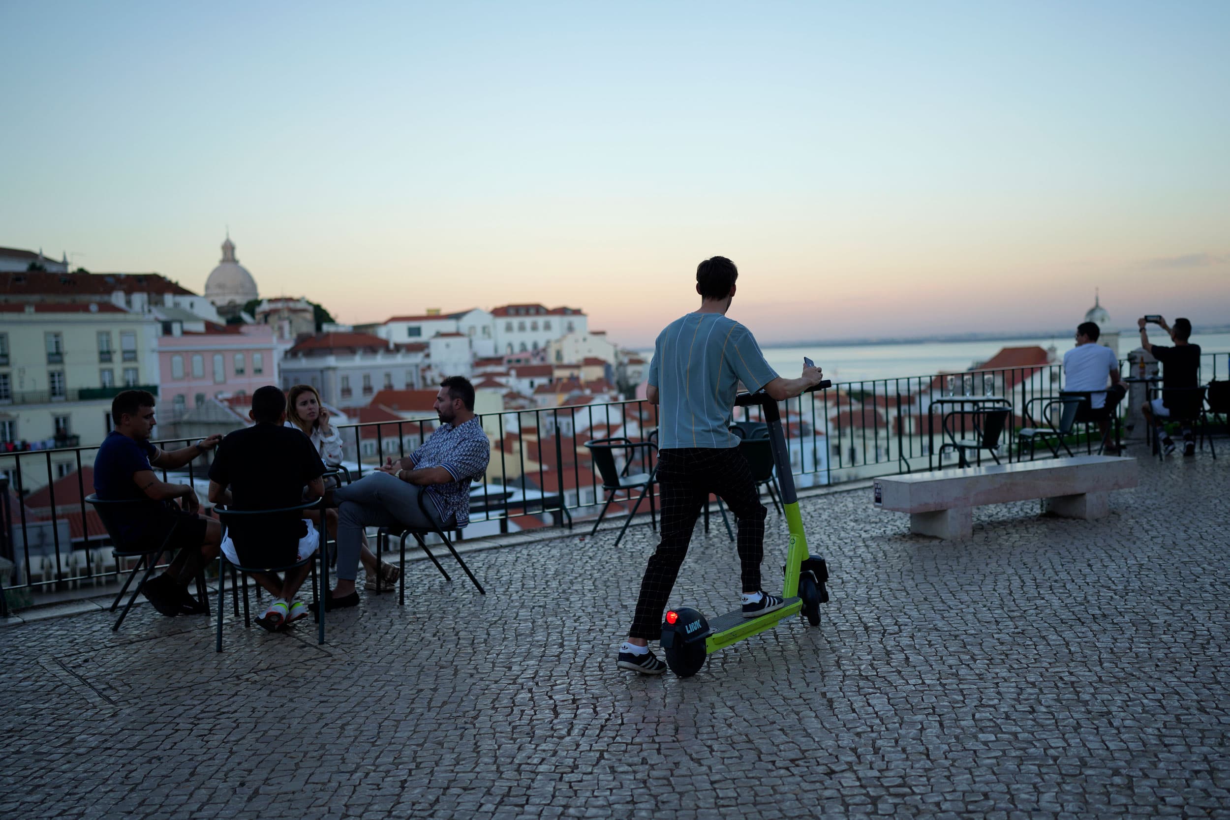 A man uses an electric scooter at a viewpoint overlooking the old Alfama neighborhood in Lisbon, Wednesday, Oct. 6, 2021.