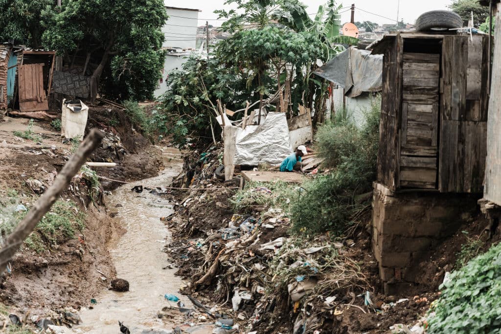 Muddy water running through an informal settlement of huts