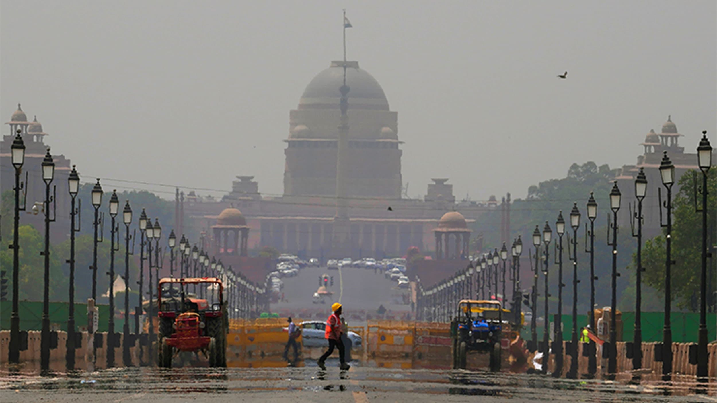 A construction worker walks across a mirage created on a road due to very hot weather in New Delhi, India