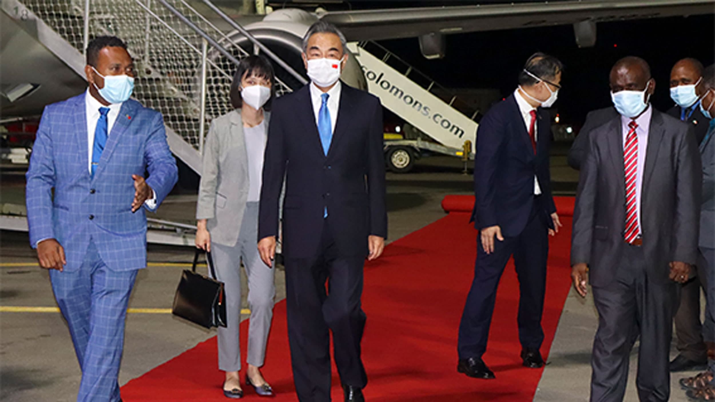 China's Foreign Minister Wang Yi, center, is escorted from his plane on his arrival in Honiara, Solomon Islands